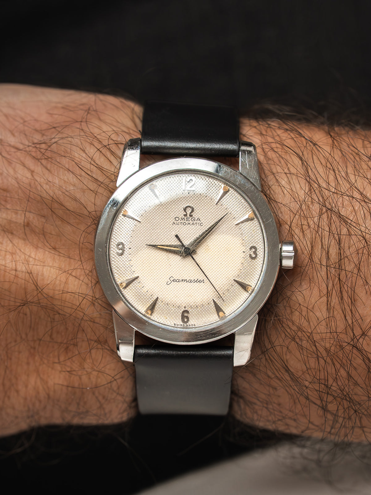 Montre Omega Seamaster vintage en acier, cadran champagne et bracelet cuir noir, au poignet