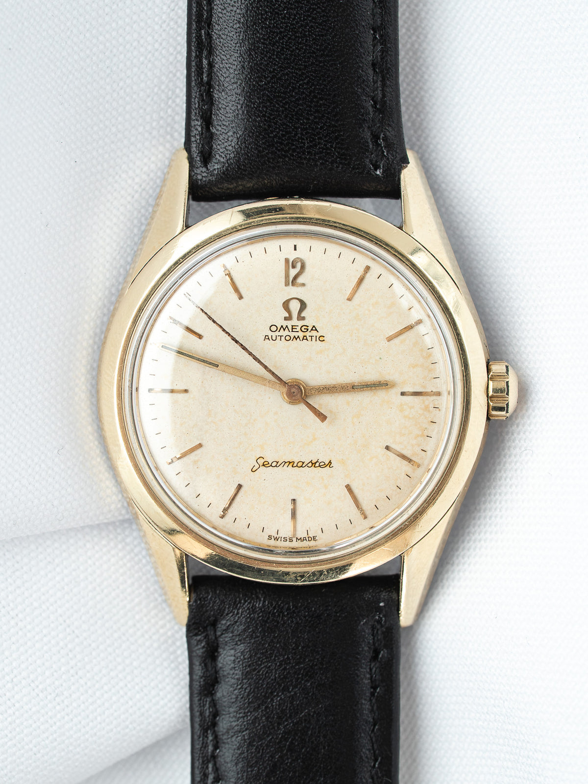 Vintage Omega Seamaster watch with gold case, cream dial, and black leather strap