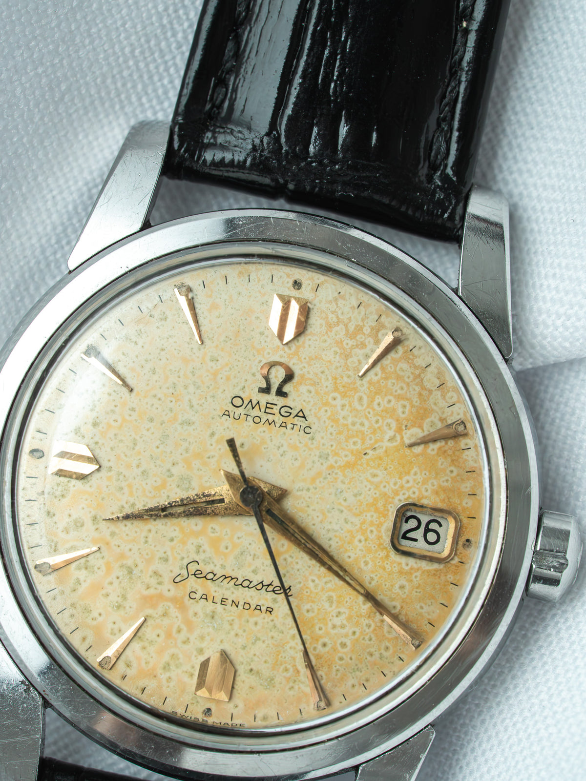 Vintage Omega Seamaster Calendar watch with aged dial, black leather strap, and date window