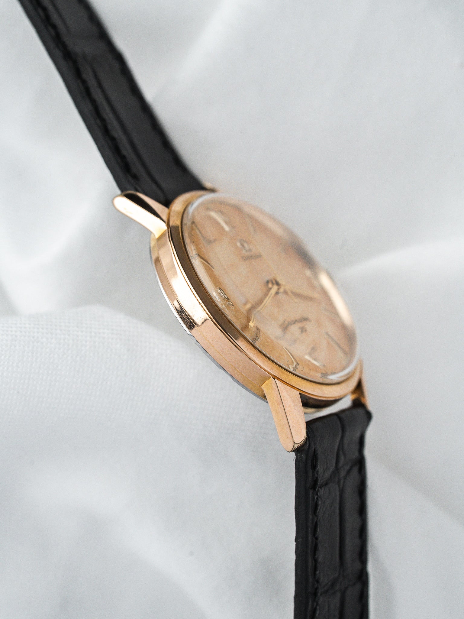 Vintage Universal Genève watch with gold case, cream dial, black leather strap
