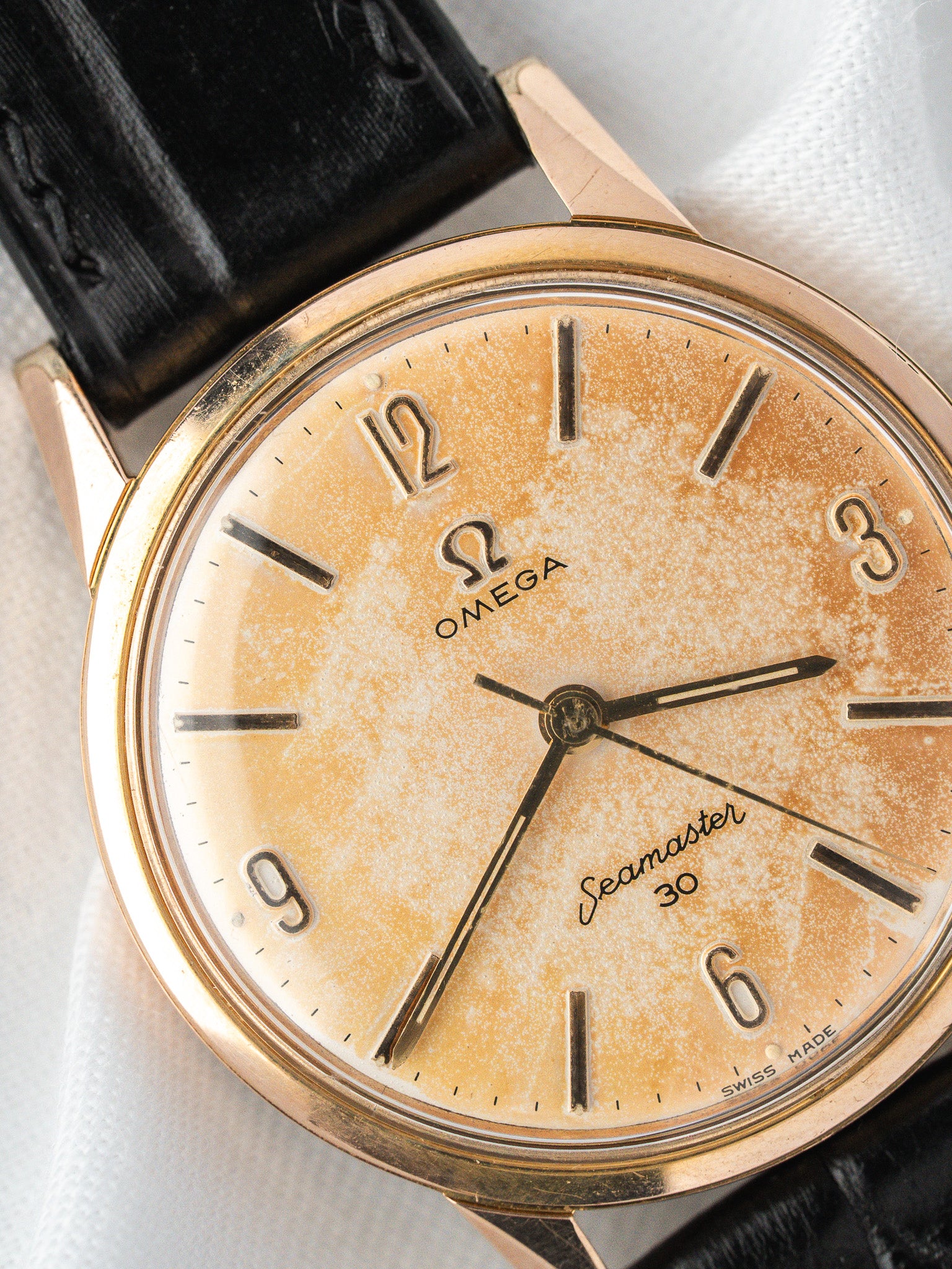 Vintage Omega Seamaster 30 watch with gold case, cream dial, and black leather strap