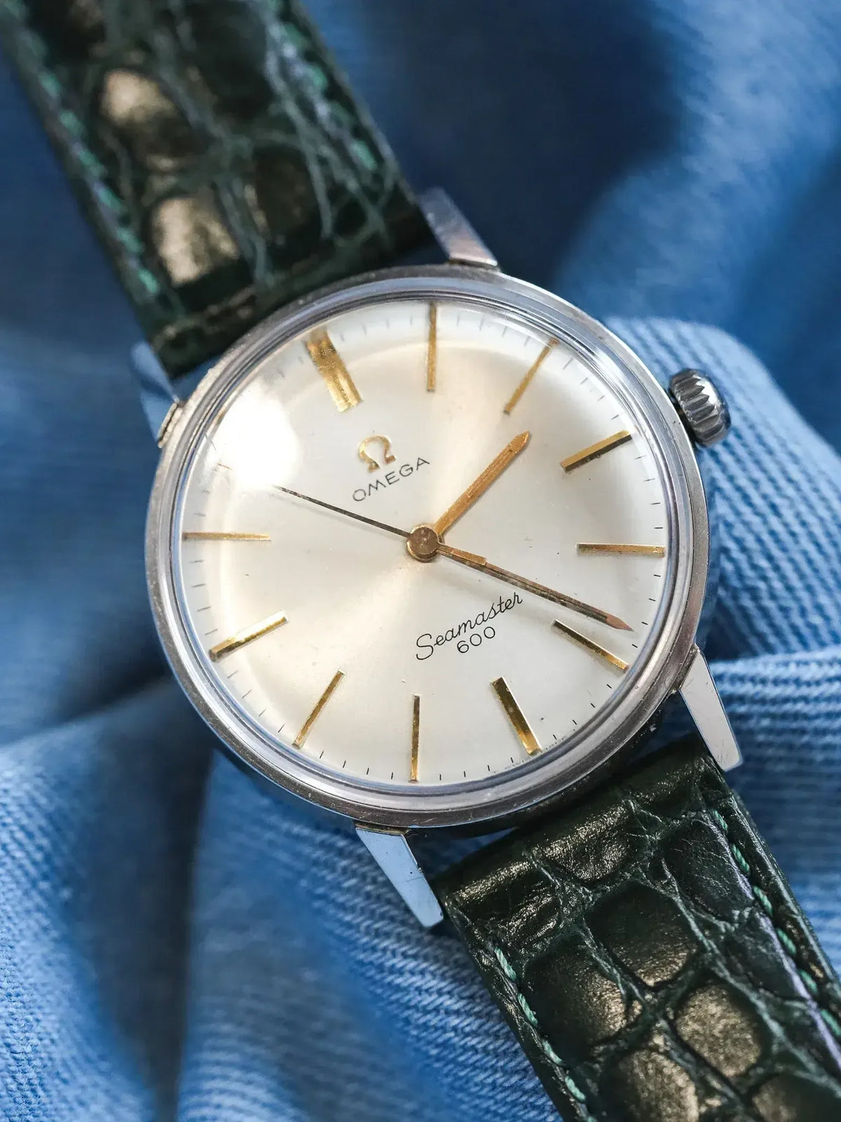 Omega Seamaster 600 vintage watch with white dial, gold markers, green alligator strap on denim