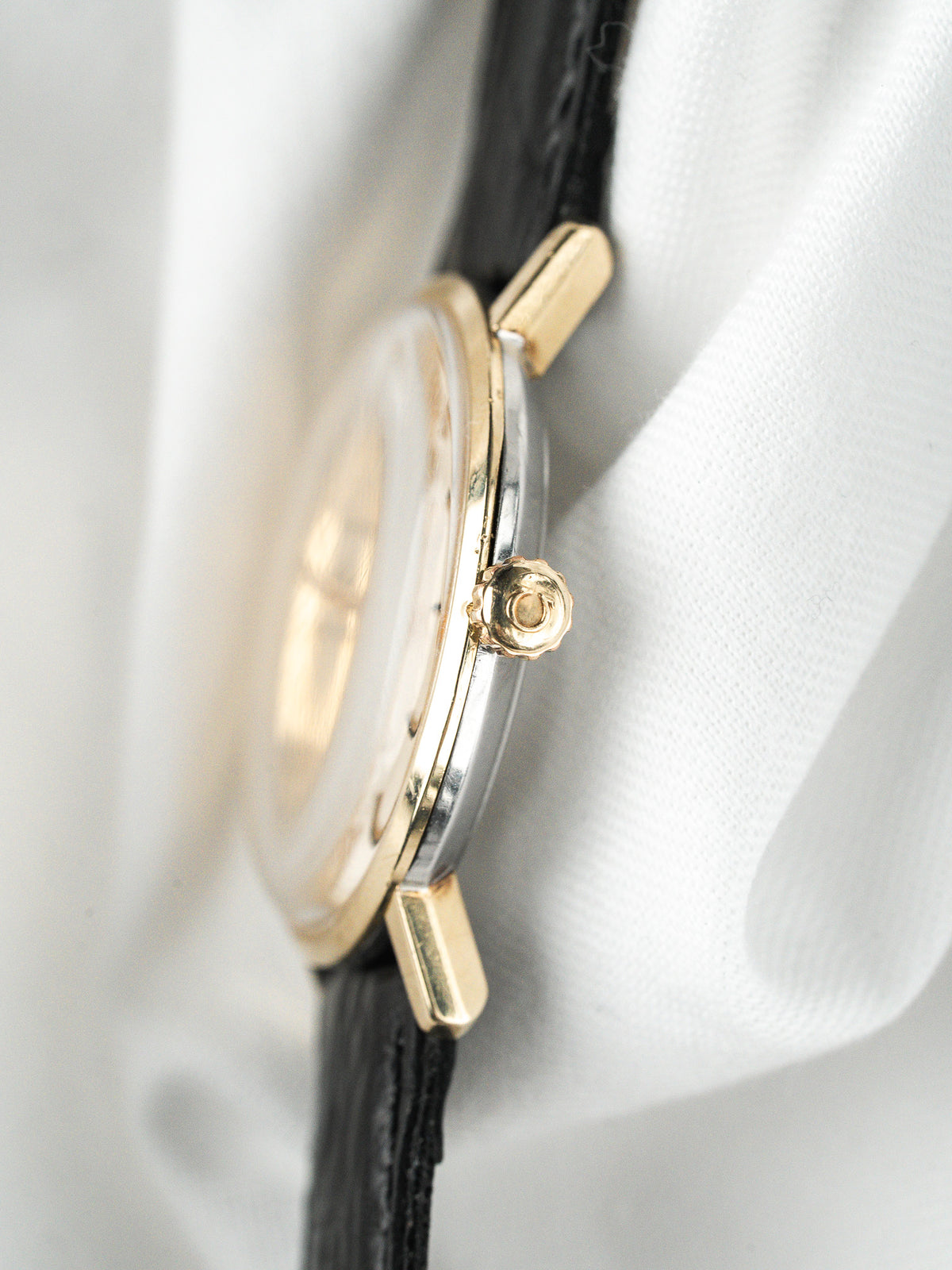 Vue de profil d'une montre vintage en or avec bracelet en cuir noir