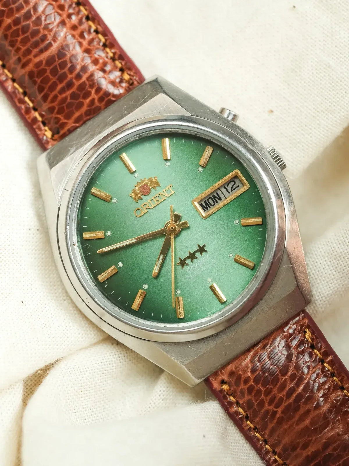 Vintage Orient watch with green dial, gold markers, and brown leather strap