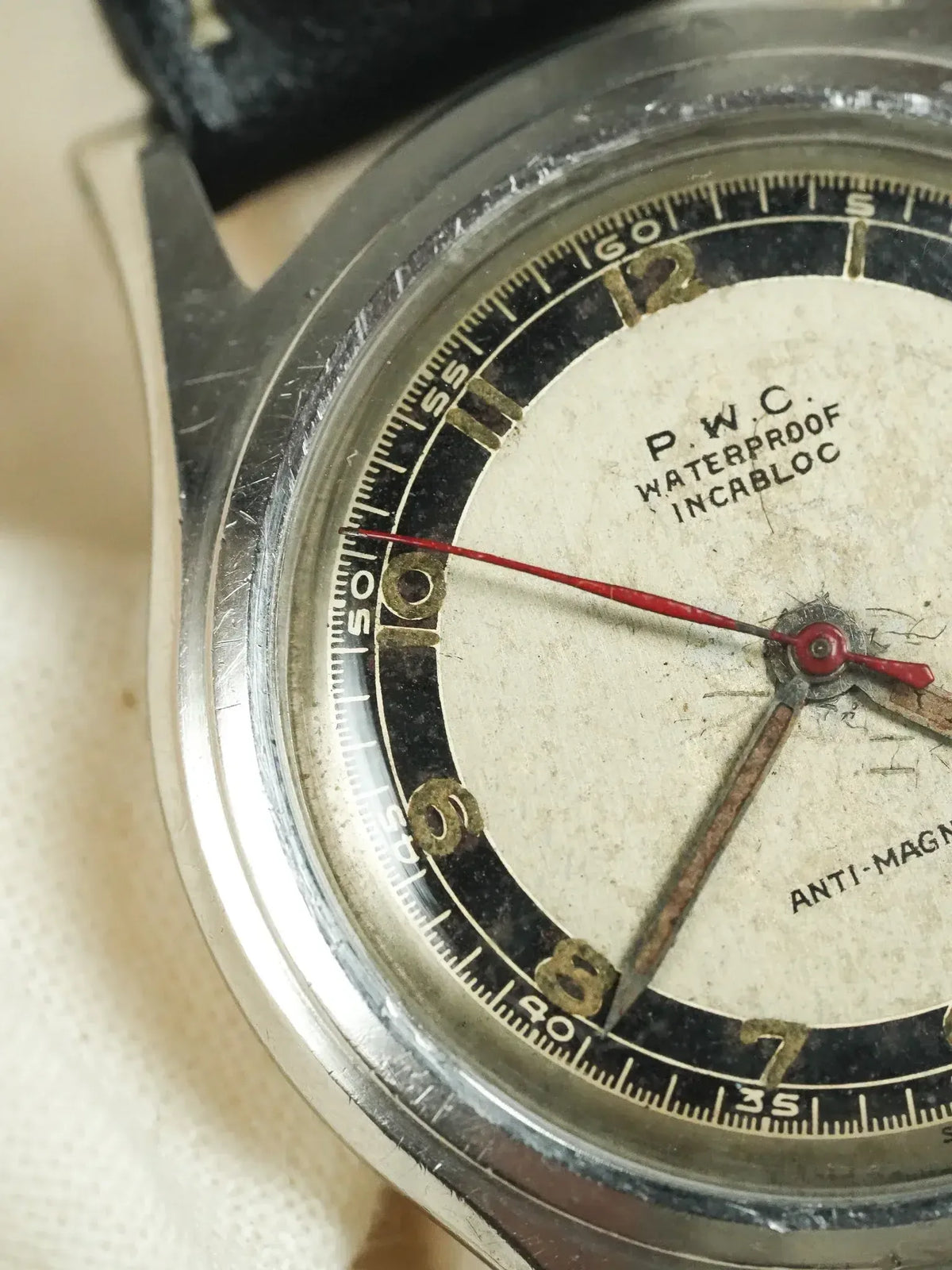 Vintage P.W.C. watch with cream dial, black chapter ring, and red seconds hand