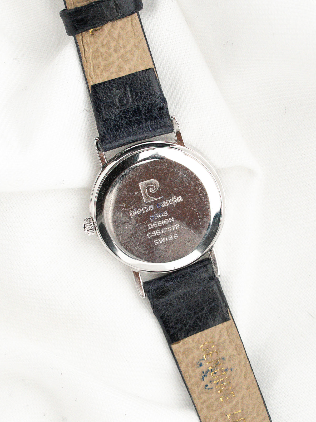 Dos d'une montre en acier avec bracelet en cuir noir et beige.