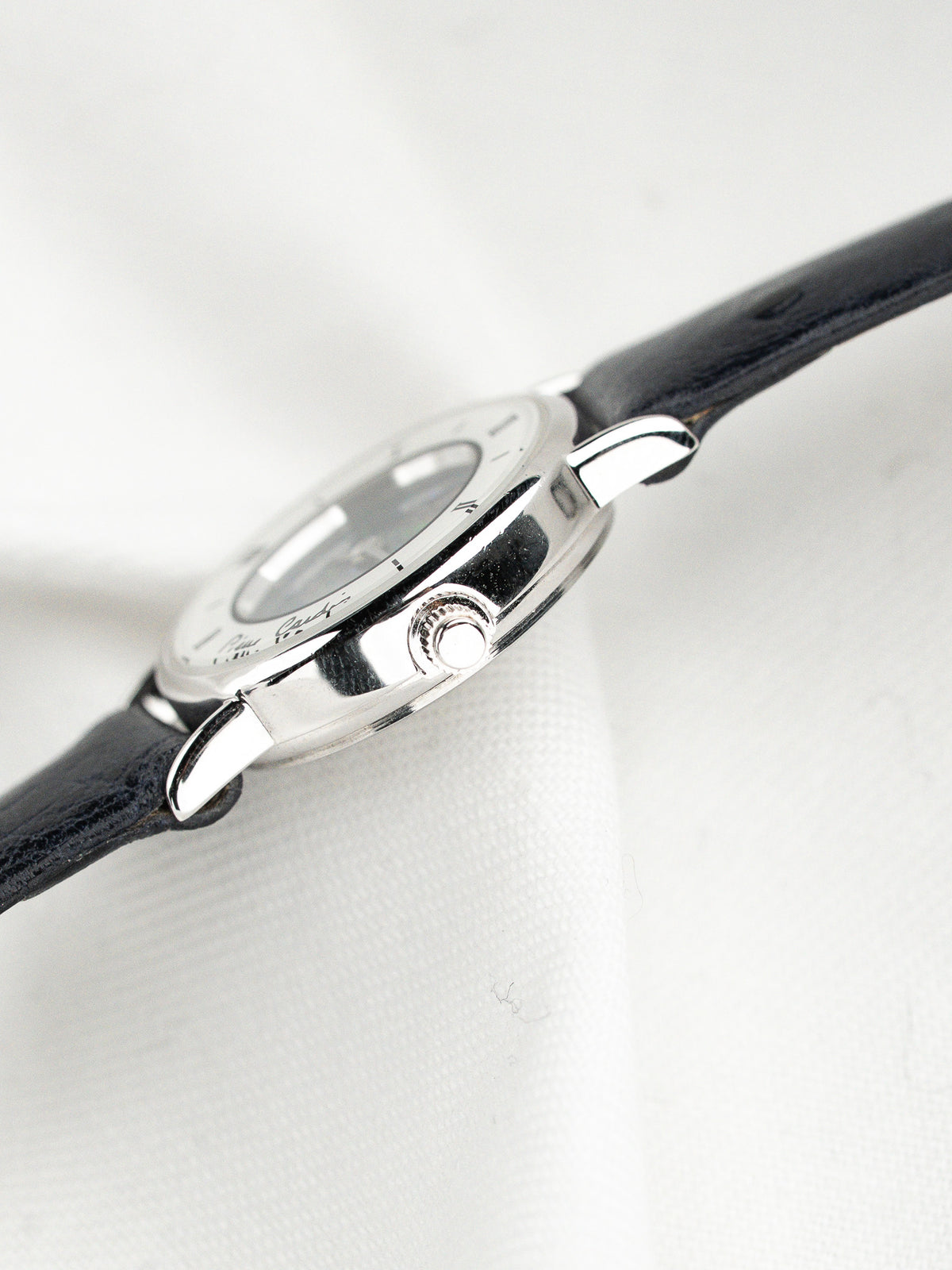 Vue de profil d'une montre avec boîtier argenté et bracelet en cuir noir.
