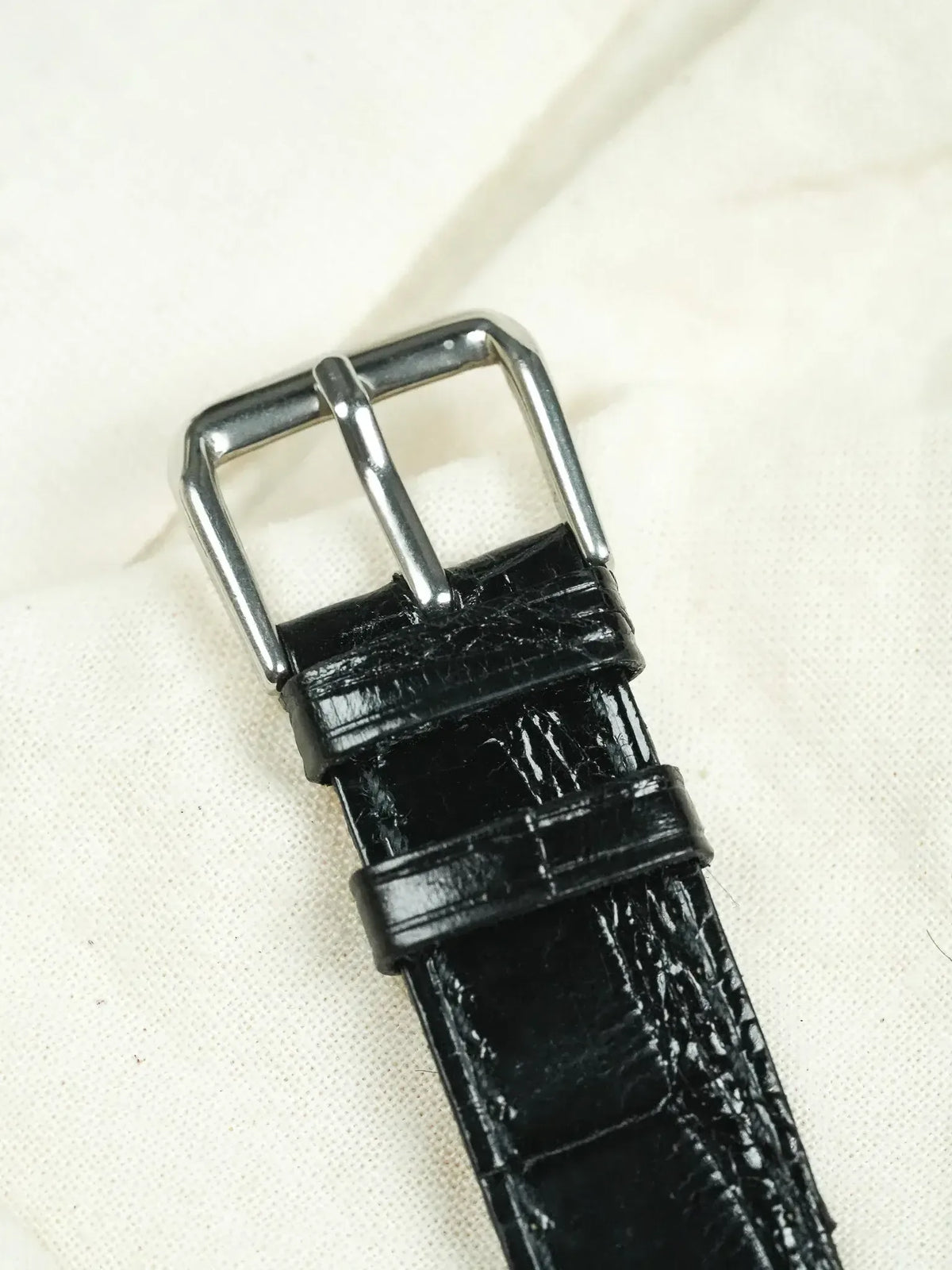 Black alligator leather watch strap with polished steel buckle on fabric