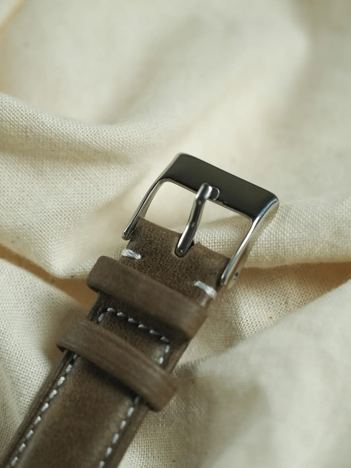 Brown suede watch strap with white stitching and polished steel buckle
