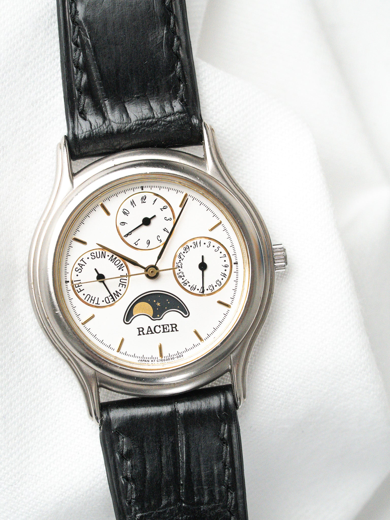 Racer vintage watch with white dial, moon phase, black leather strap on white background
