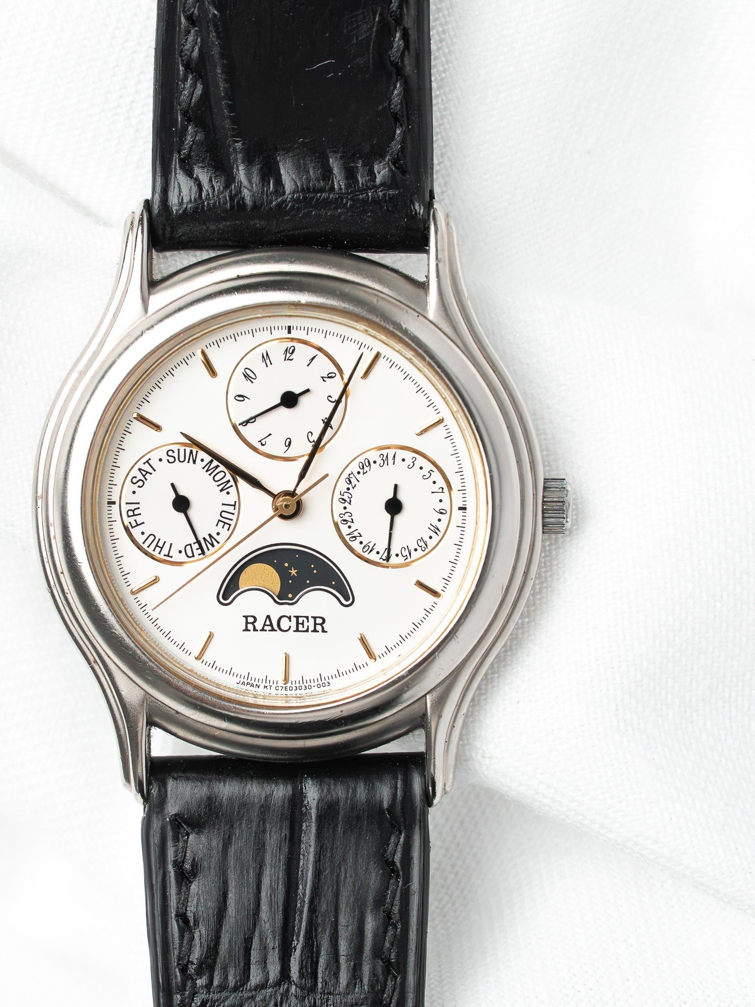 Racer vintage watch with white dial, moon phase, black leather strap on white background
