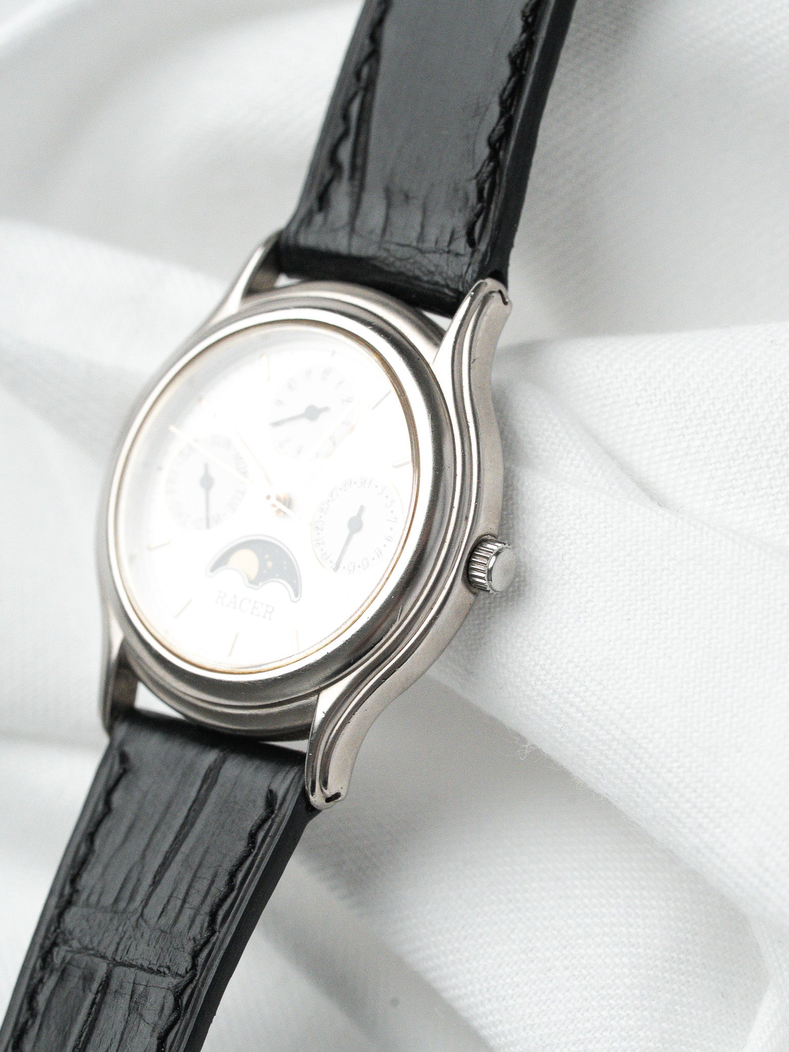 Racer vintage watch with white dial, moon phase, black leather strap on white fabric