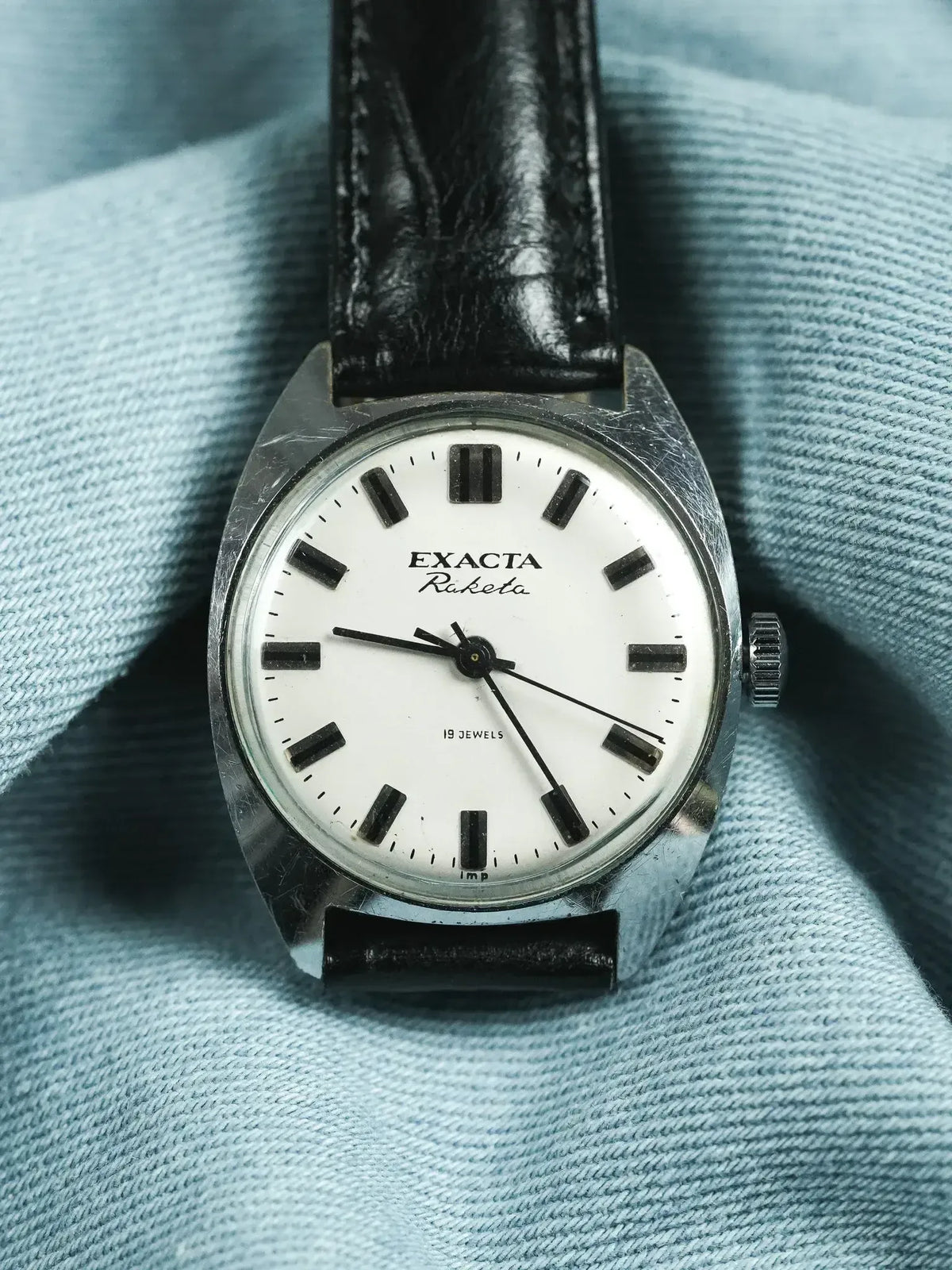 Exacta Raketa vintage watch with white dial, black markers, and black leather strap