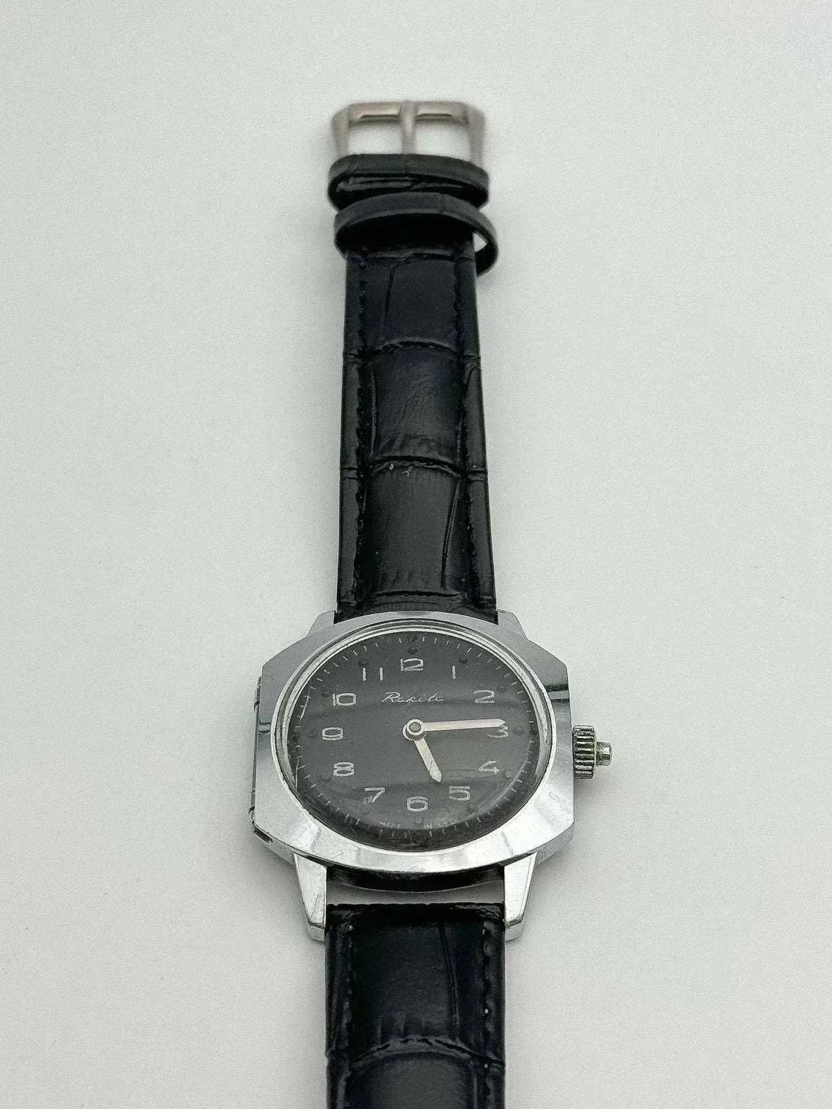 Rolex vintage watch with black dial, steel case, and black alligator strap on white background