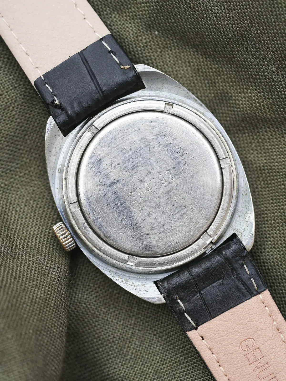 Vintage Universal Genève watch back, stainless steel case, black leather strap on olive fabric