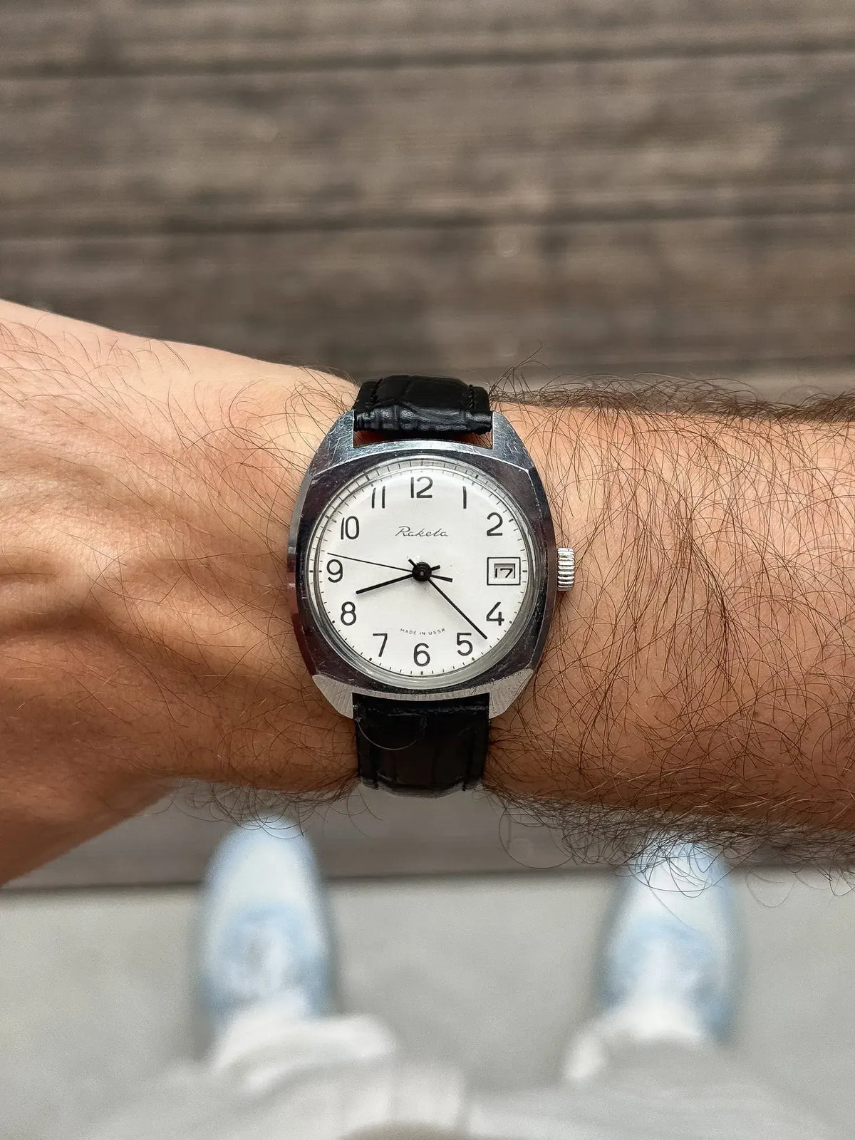 Raketa vintage watch with white dial, black leather strap, worn on wrist