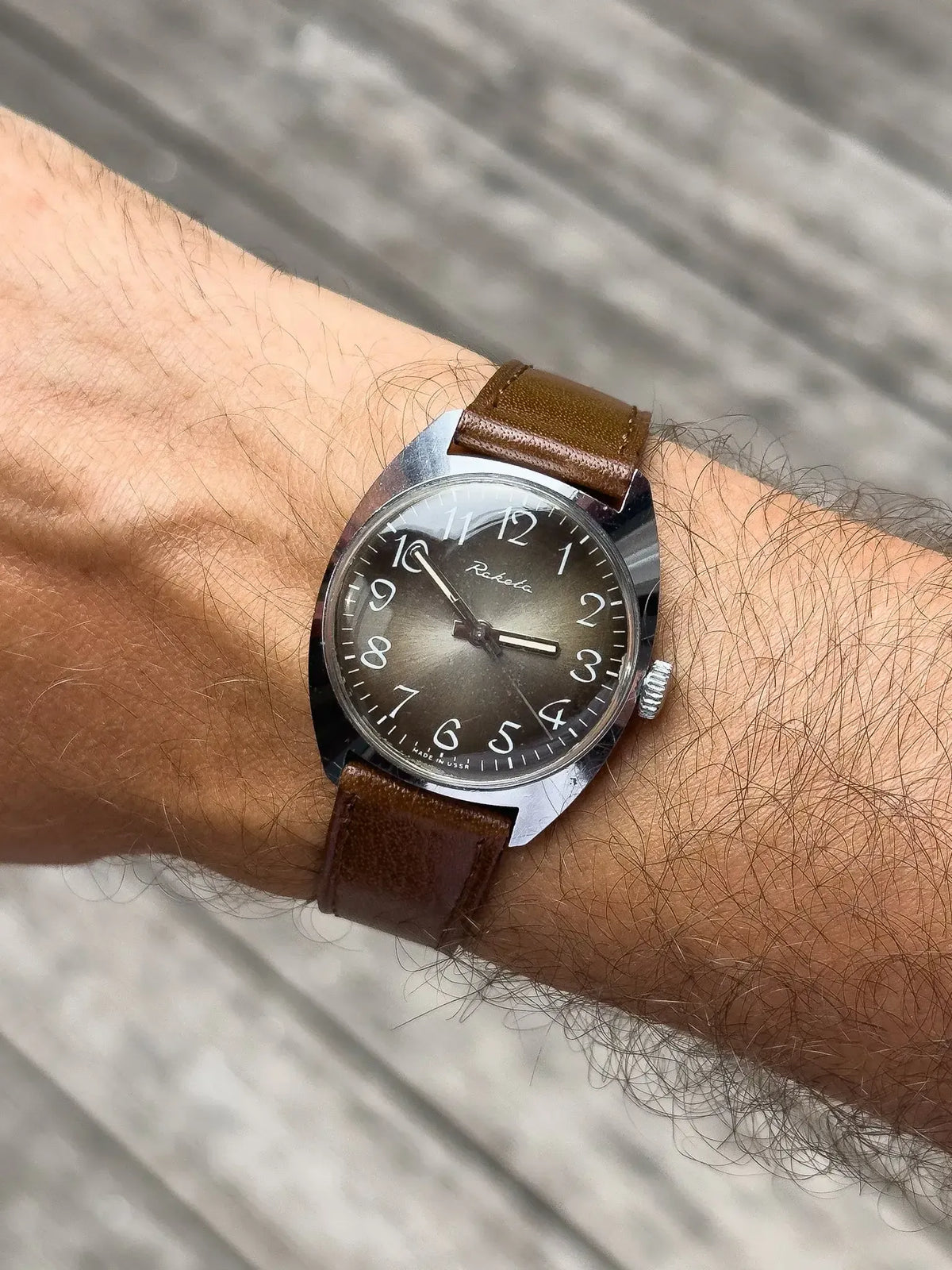 Raketa vintage watch with brown leather strap, silver case, and dark dial on wrist