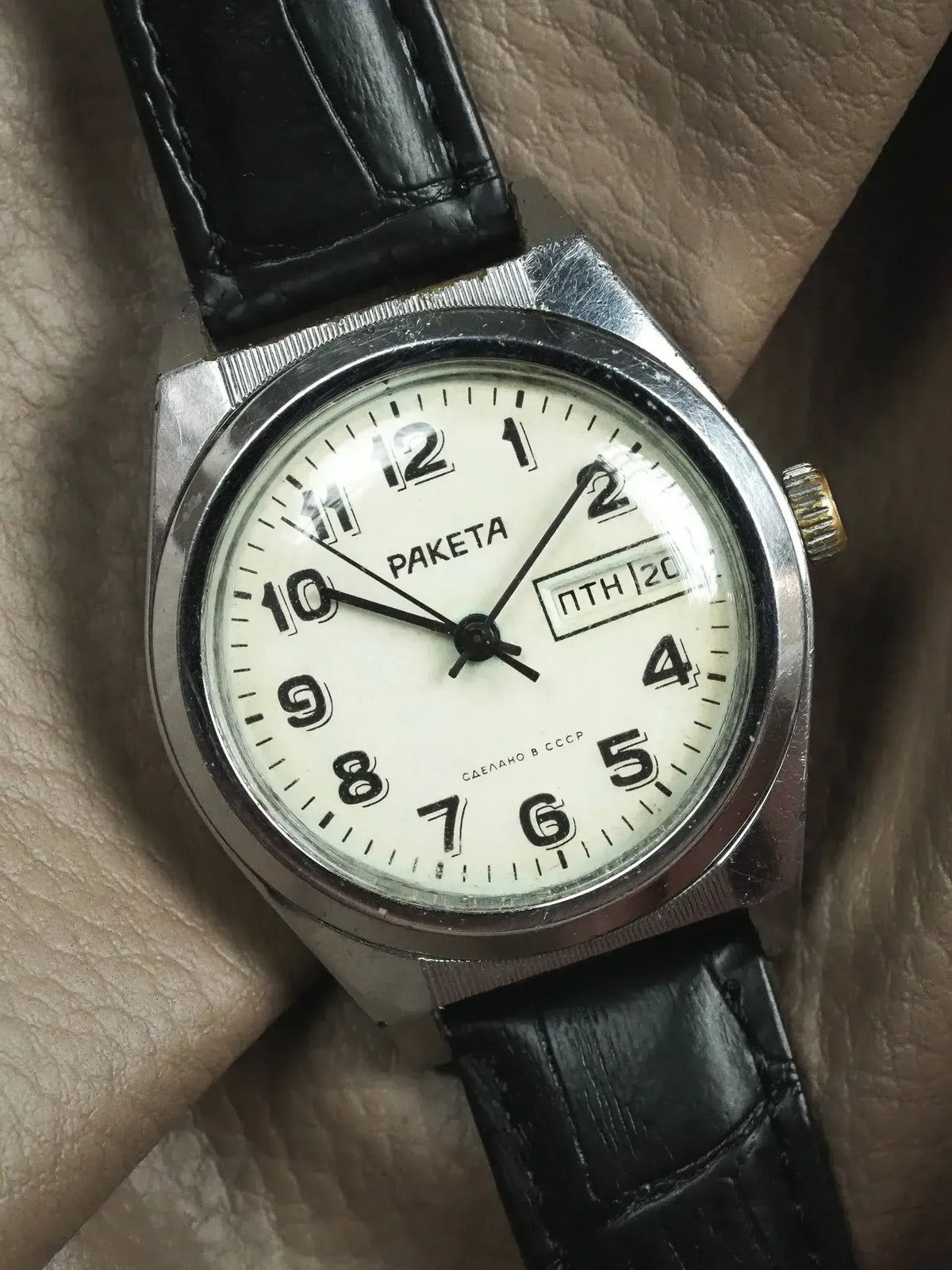 Raketa vintage watch with white dial, black leather strap, and Soviet-era Cyrillic text