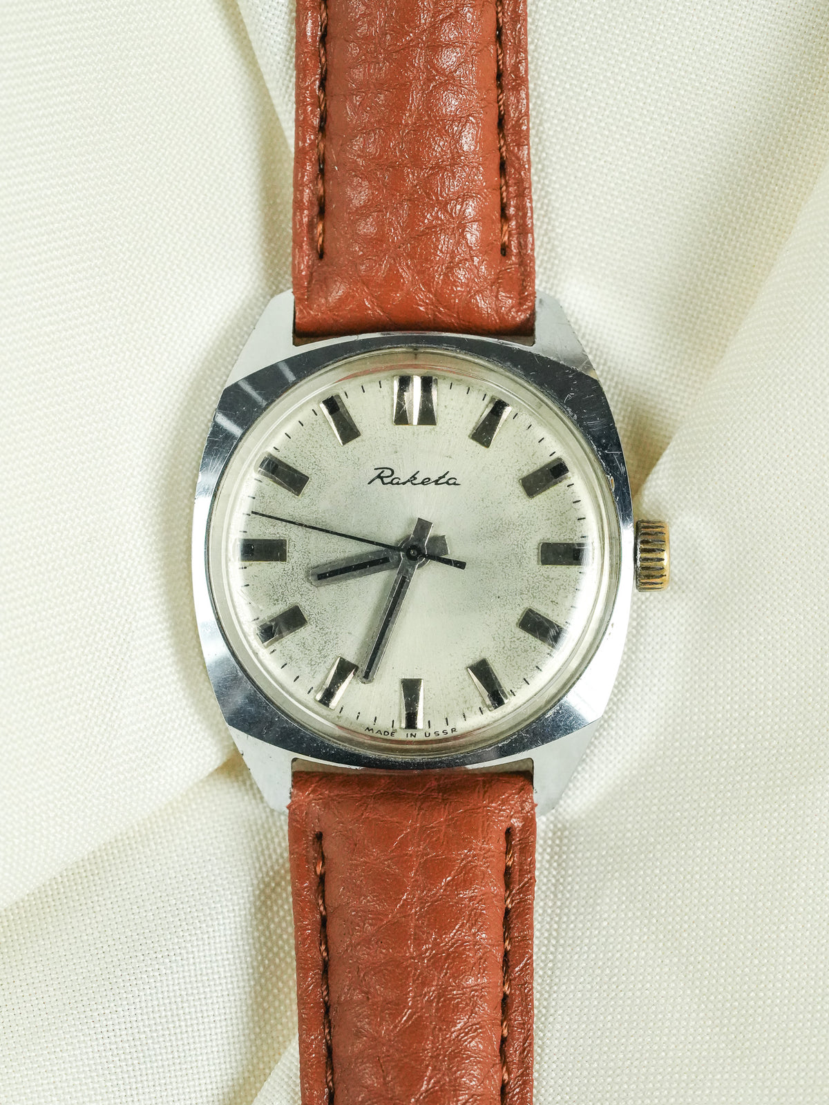 Raketa vintage watch with white dial, brown leather strap, and steel case