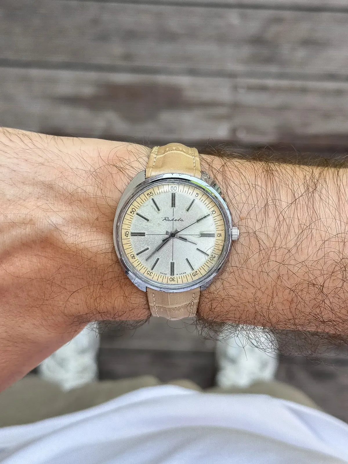 Raketa vintage watch with cream dial, steel case, tan leather strap on wrist