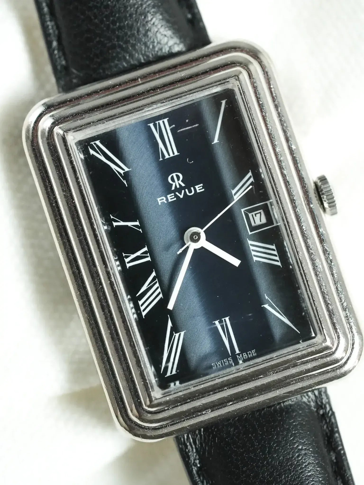 Revue vintage watch with black dial, Roman numerals, and black leather strap