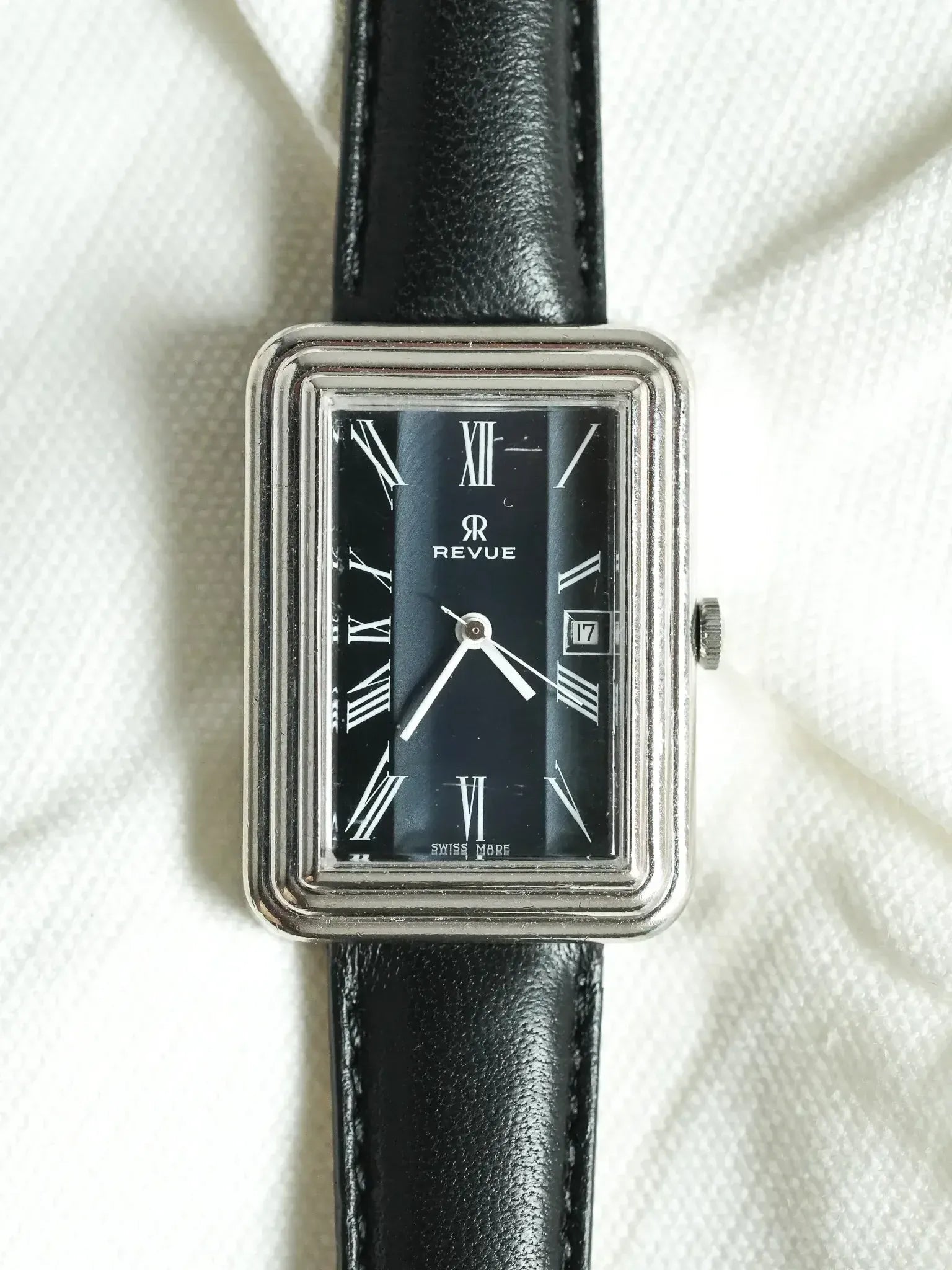Revue vintage watch with black dial, Roman numerals, and black leather strap