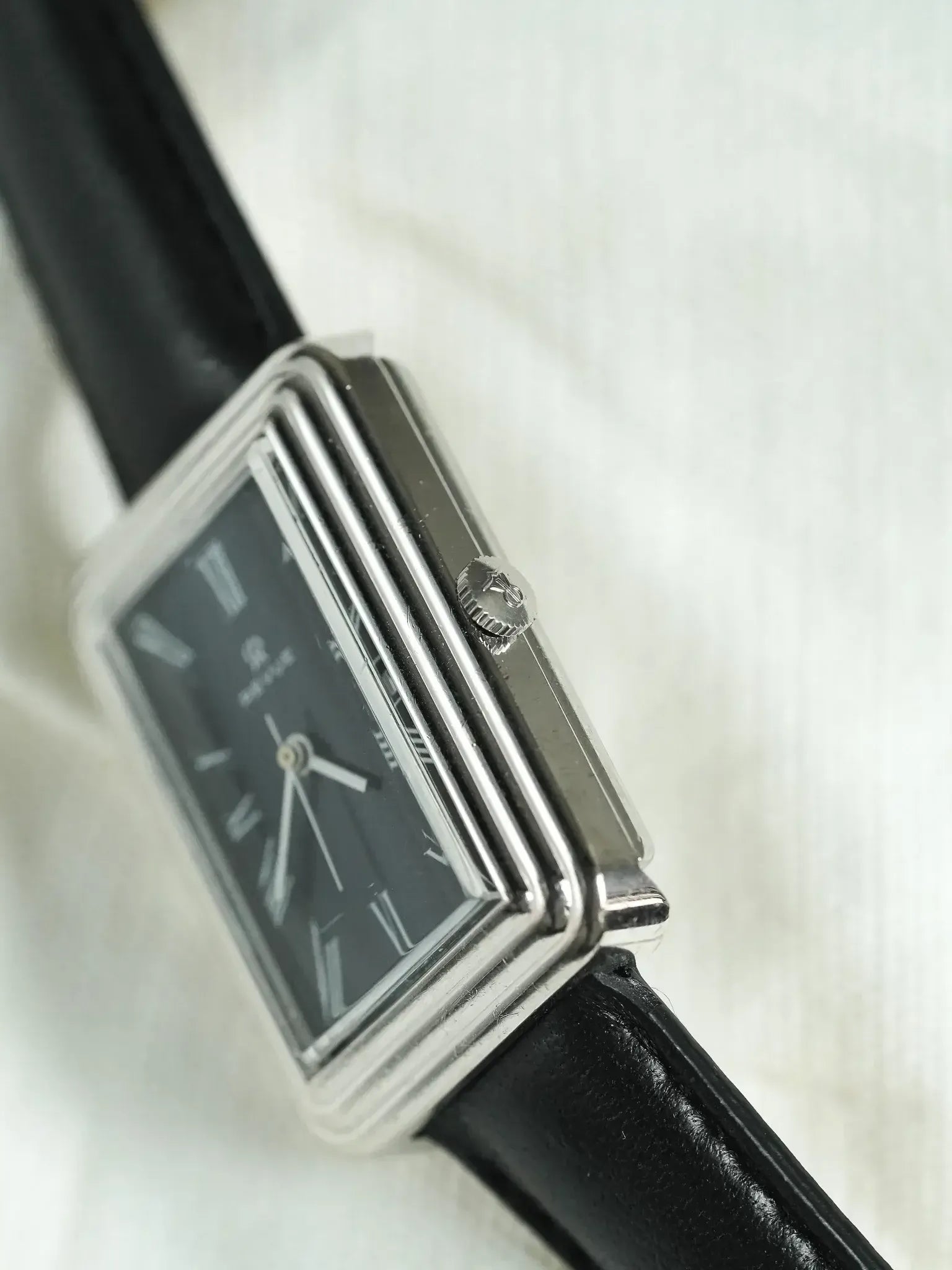 Rolex vintage rectangular watch with black dial, silver case, and black leather strap