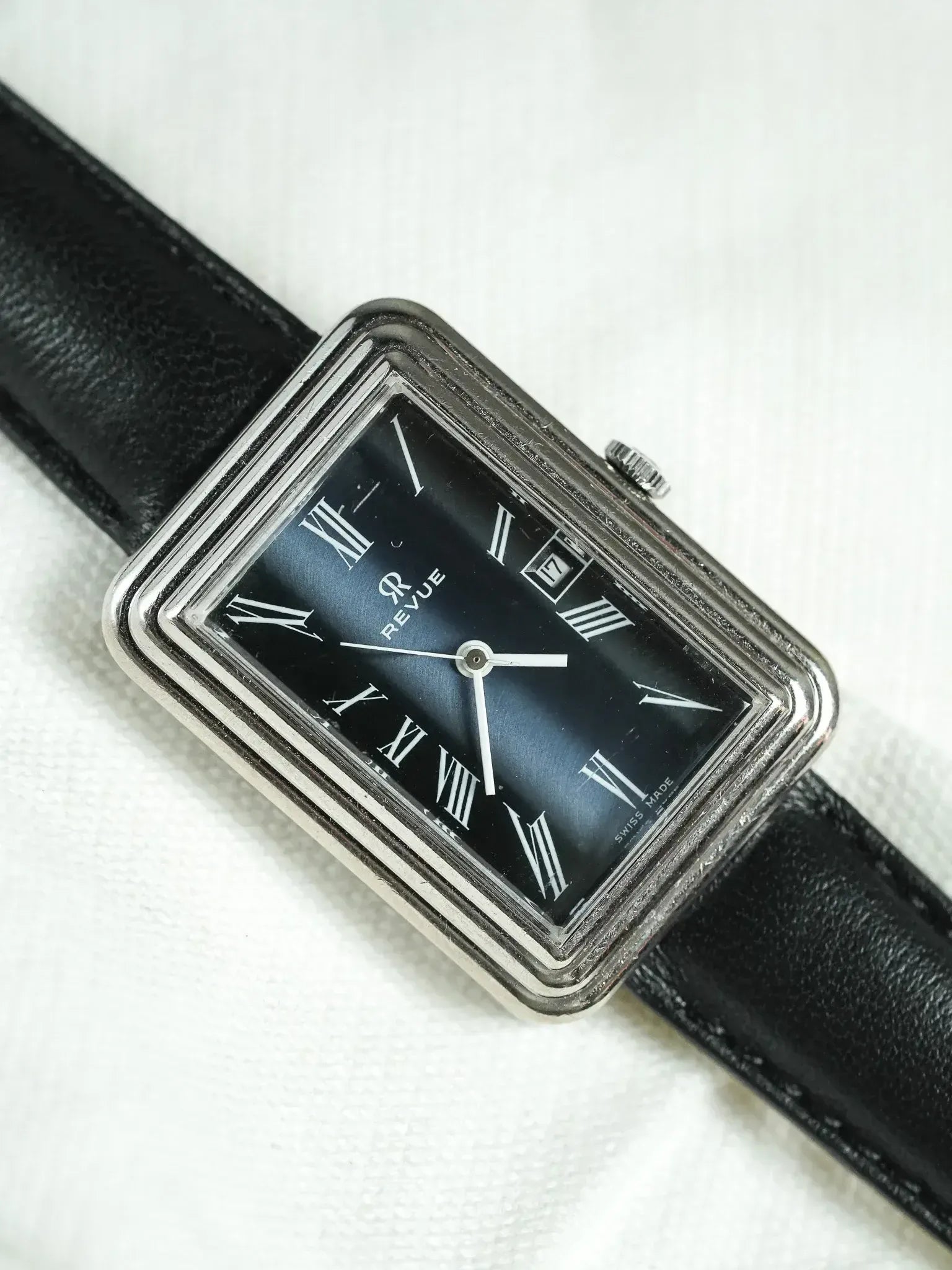 Revue vintage watch with black dial, Roman numerals, and black leather strap