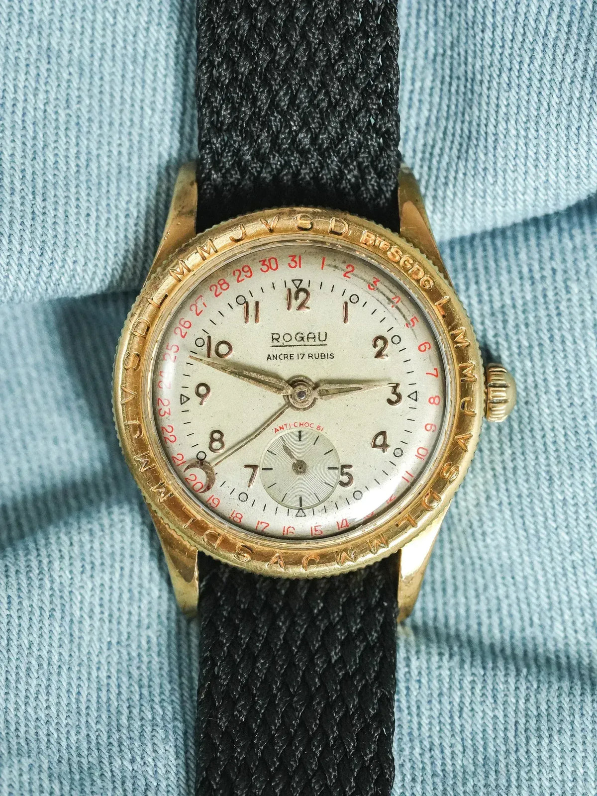 Vintage Rogau watch with gold case, white dial, red date, black fabric strap