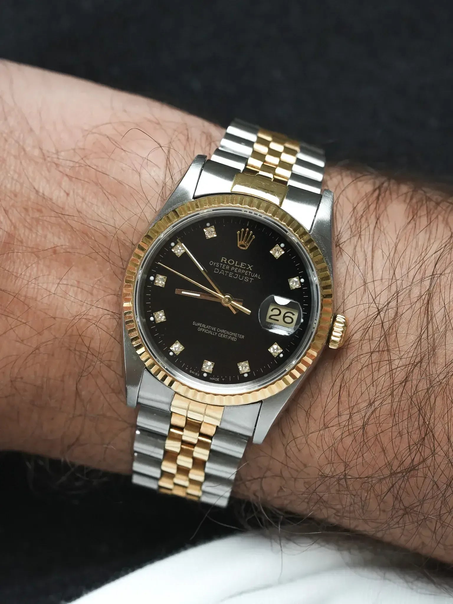 Rolex Datejust vintage with black diamond dial, two-tone steel and gold bracelet worn on wrist