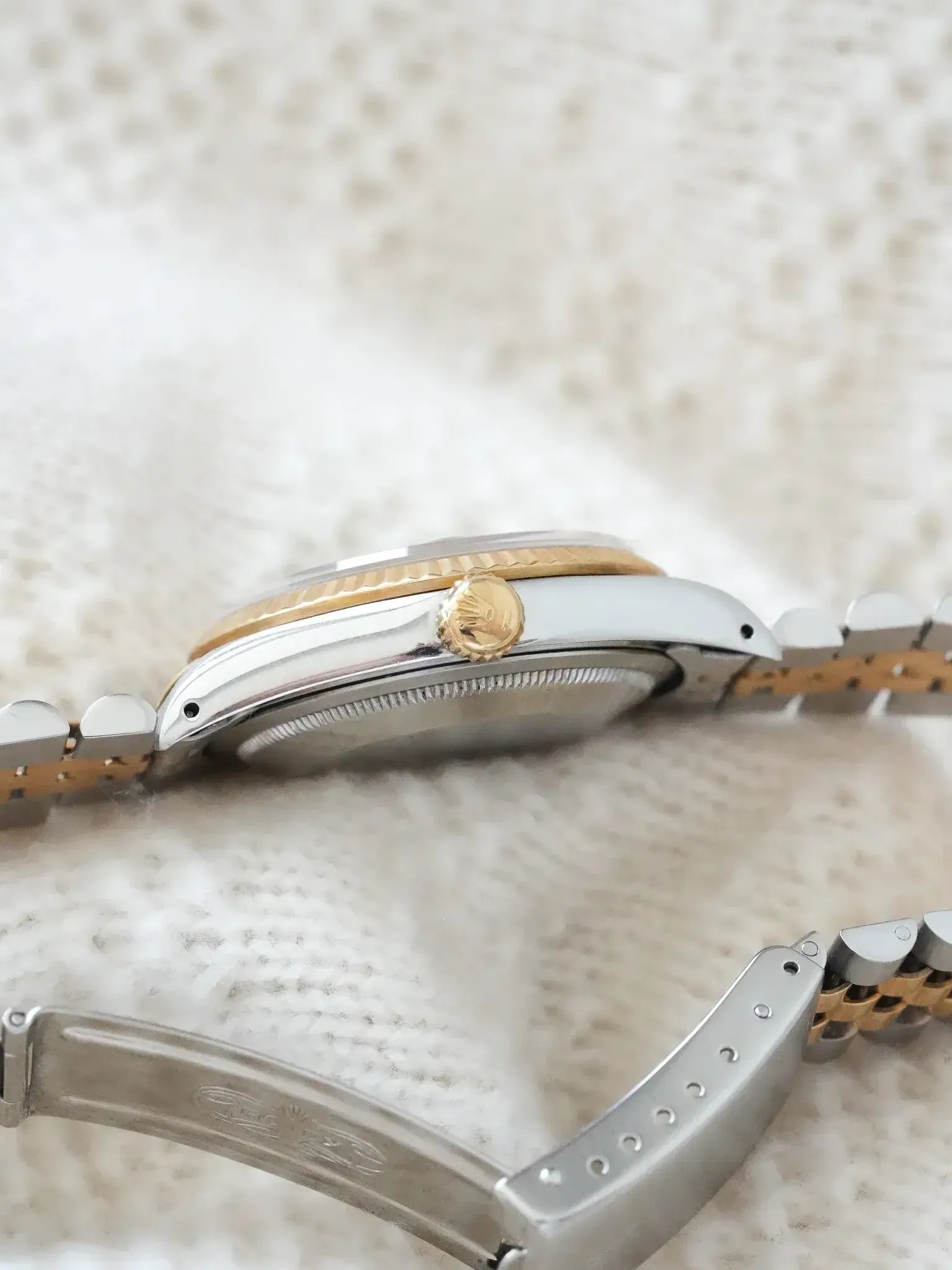 Rolex vintage watch with two-tone steel and gold bracelet, side view on textured fabric