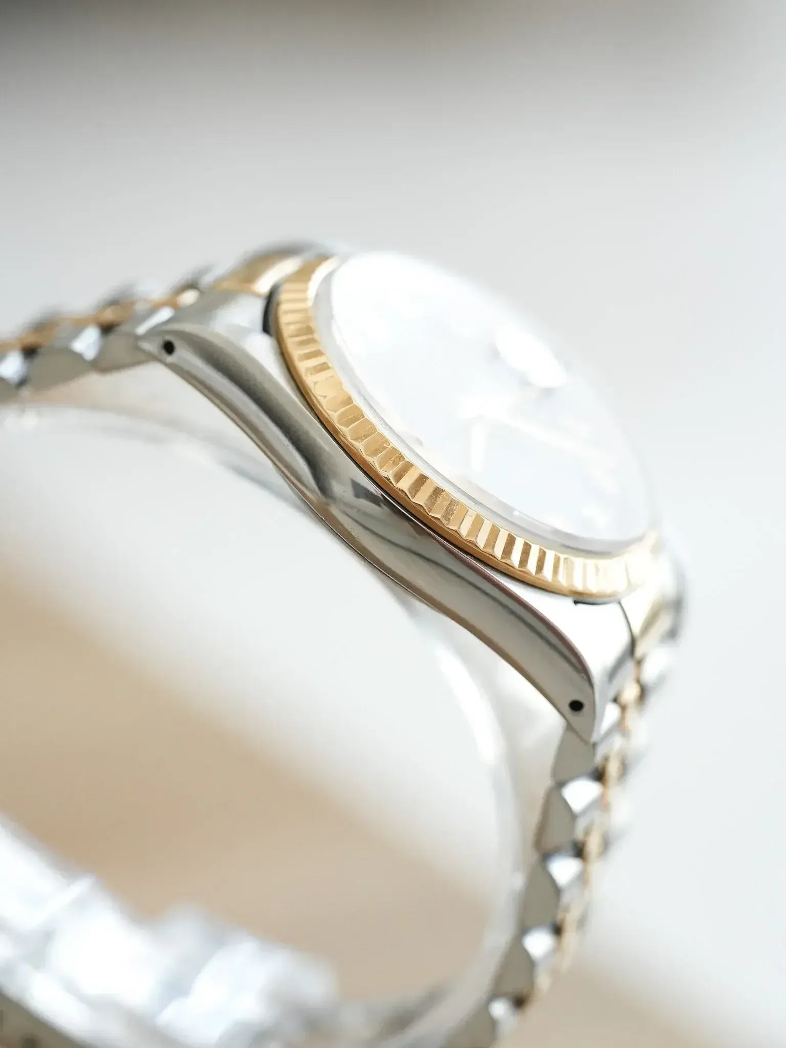Rolex vintage watch with white dial, gold bezel, and two-tone steel bracelet
