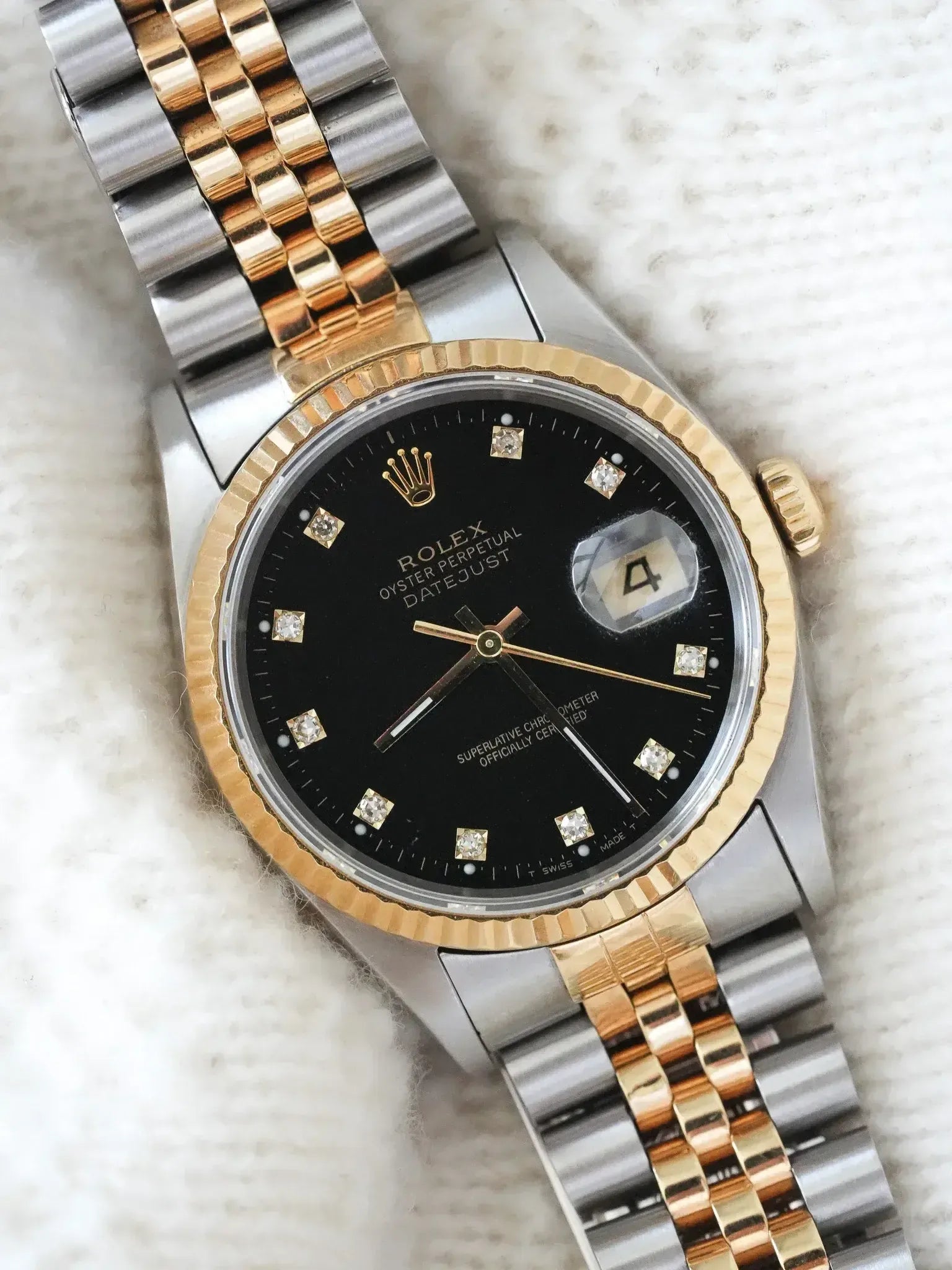 Rolex Datejust vintage with black diamond dial, two-tone bracelet on textured white background