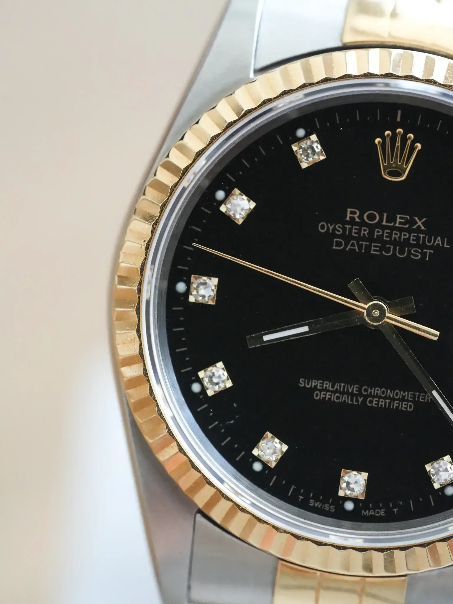 Rolex Datejust vintage with black dial, diamond hour markers, gold bezel, and two-tone bracelet