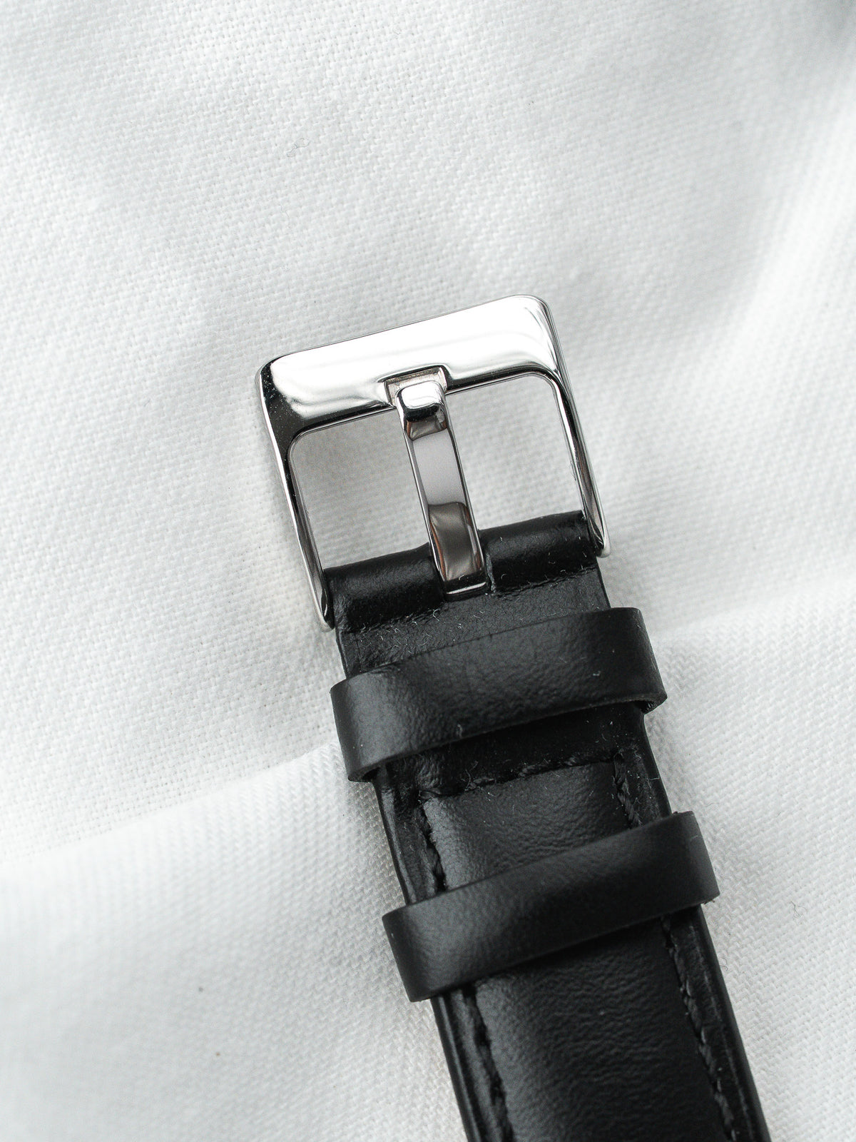 Bracelet de montre en cuir noir avec boucle ardillon en acier sur fond blanc