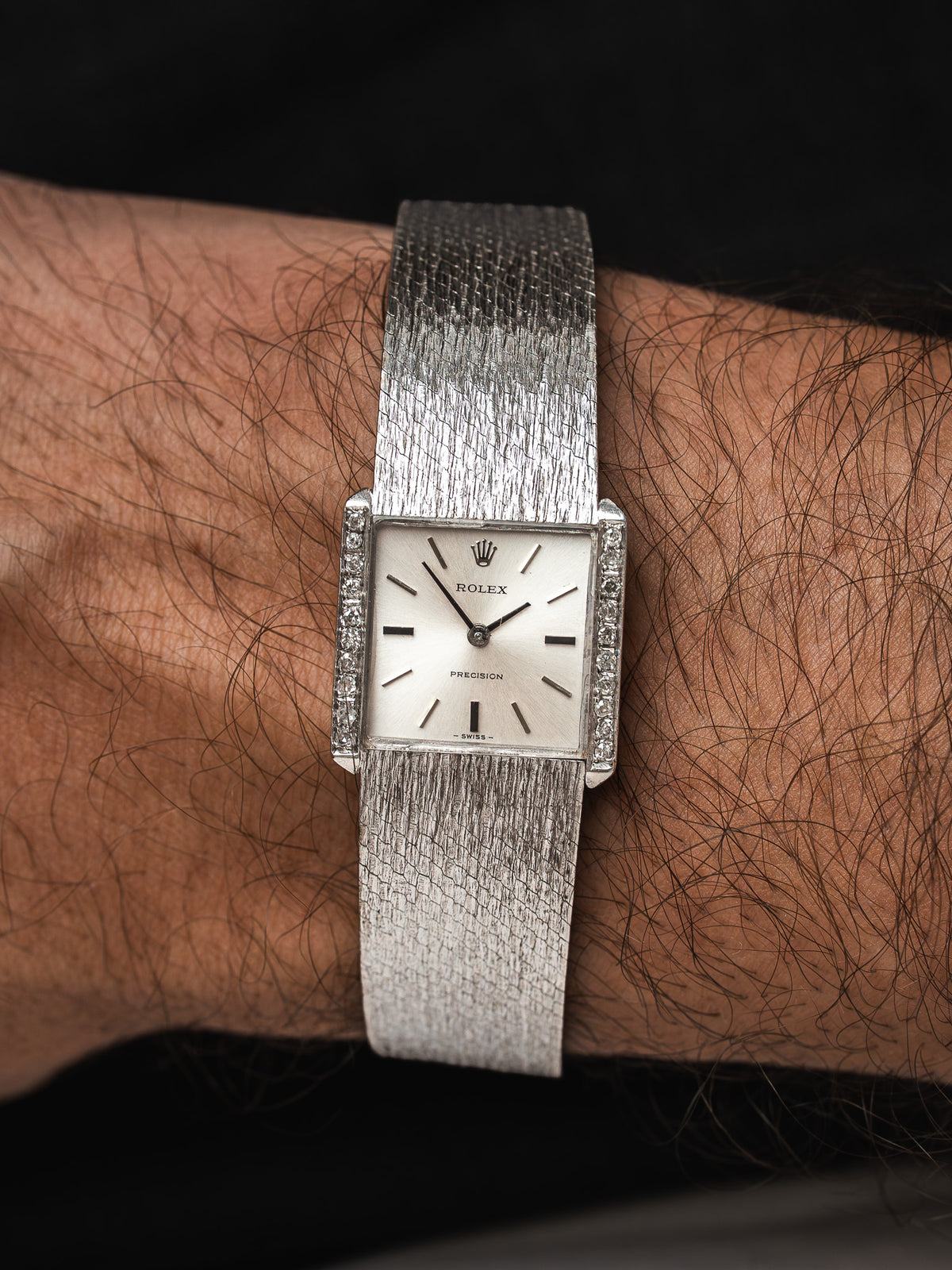 Montre Rolex vintage rectangulaire en argent, cadran blanc, portée au poignet