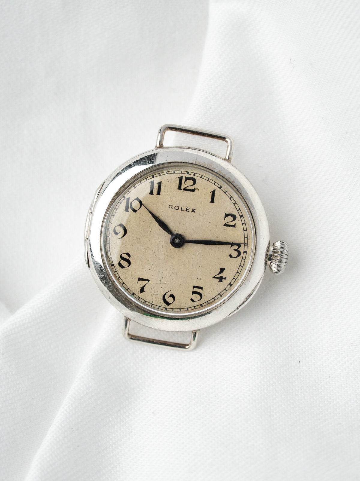Montre Rolex vintage en acier avec cadran crème sur fond de tissu blanc