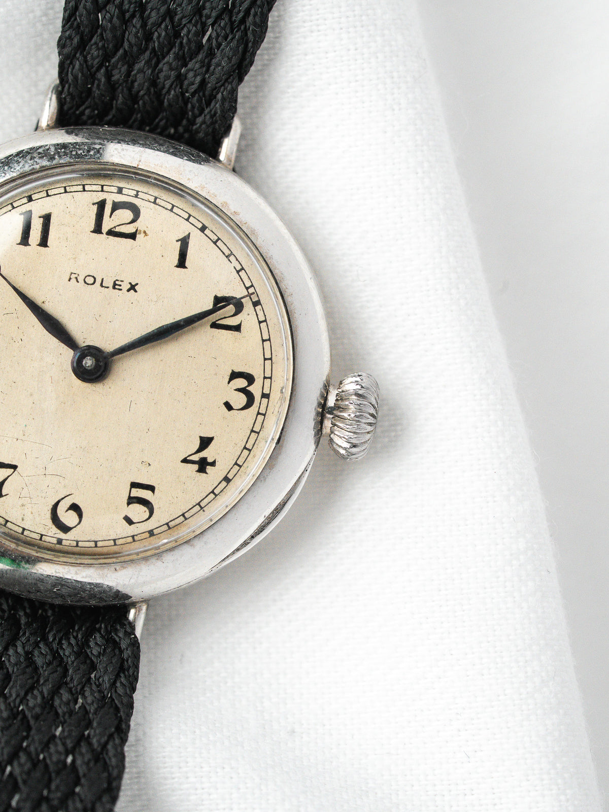 Montre Rolex vintage, boîtier rond argenté, cadran beige et bracelet textile noir