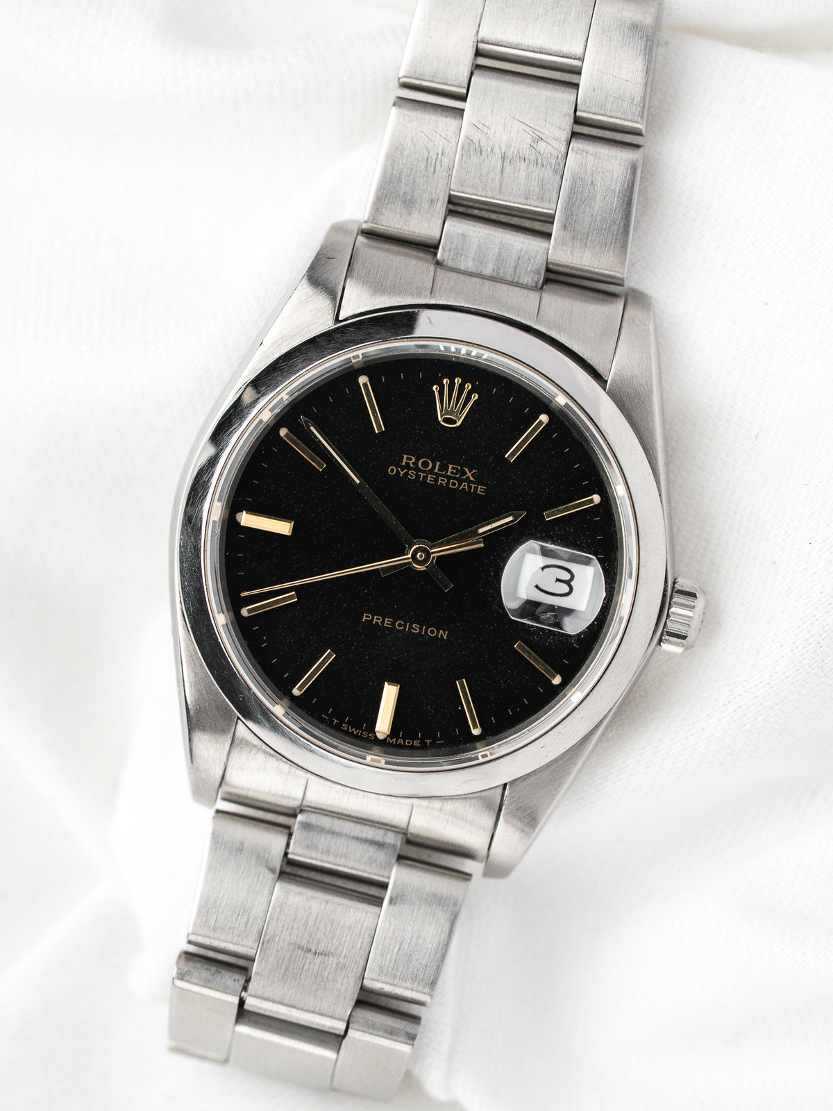 Montre Rolex Oysterdate vintage en acier, cadran noir et bracelet métallique, fond blanc