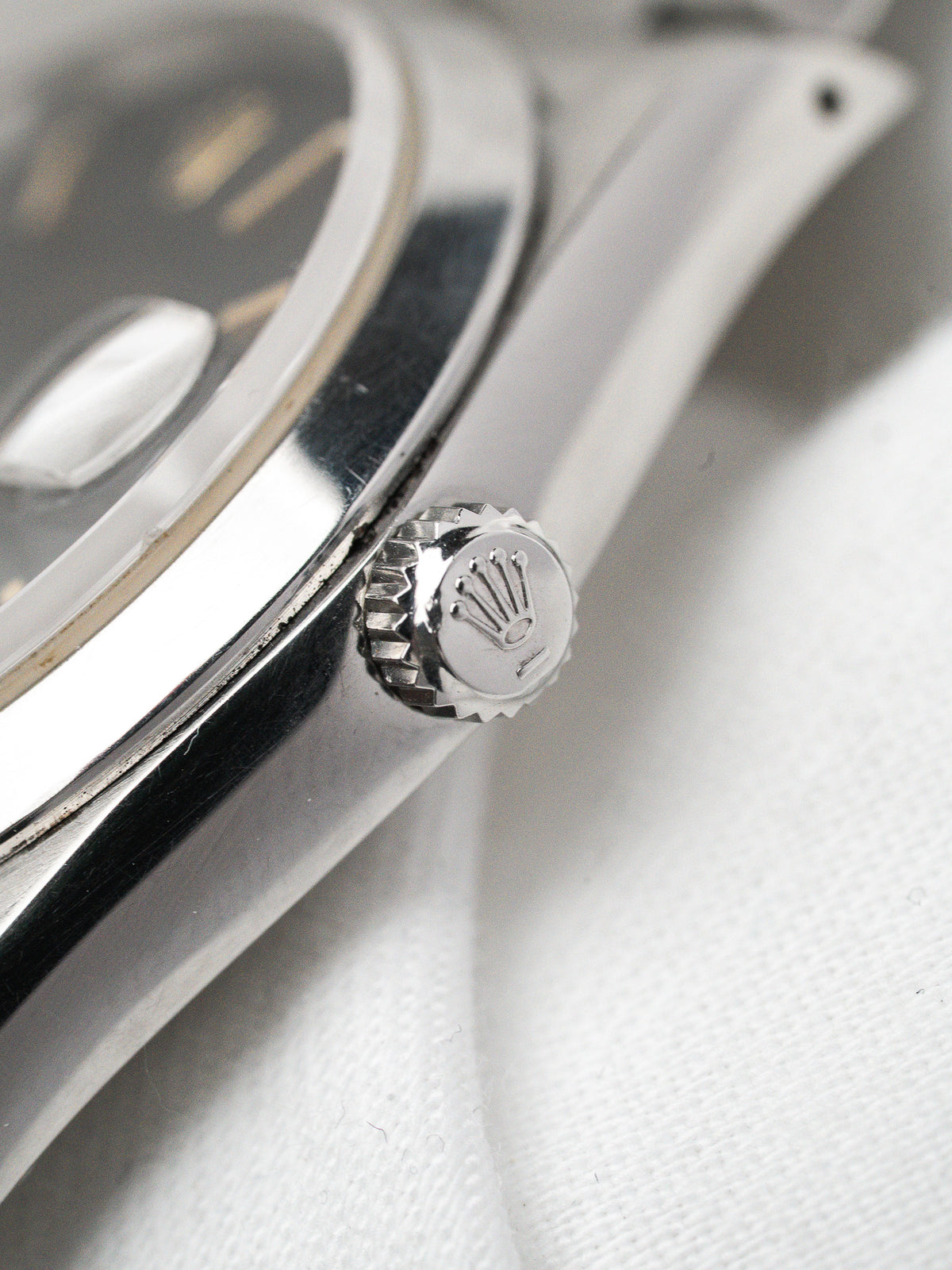 Détail de la couronne en acier d'une montre Rolex sur fond blanc