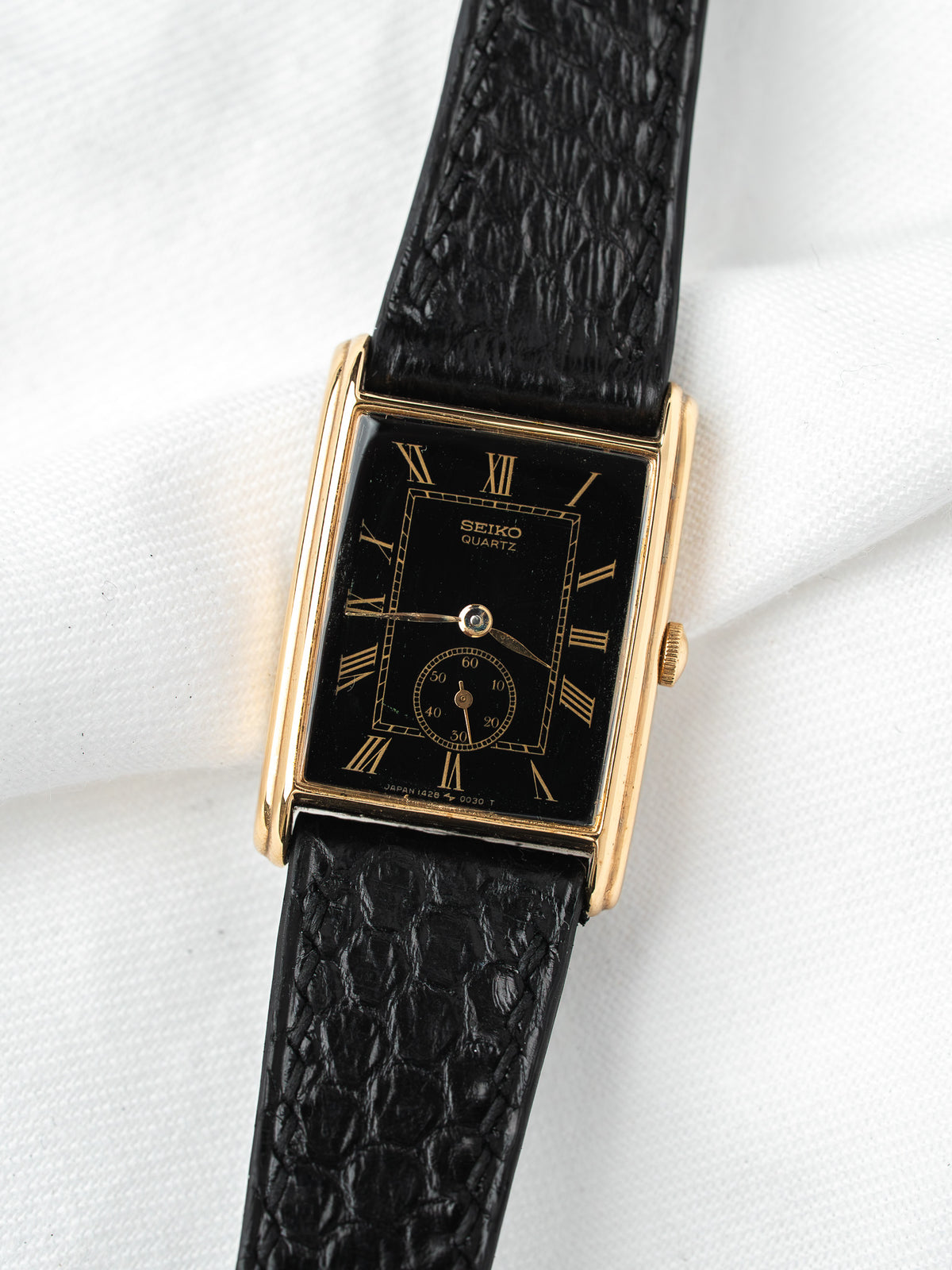 Seiko Quartz vintage watch with black dial, gold case, and textured leather strap