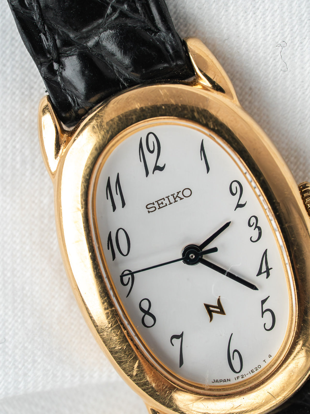 Montre Seiko vintage, boîtier ovale plaqué or, cadran blanc et bracelet cuir noir