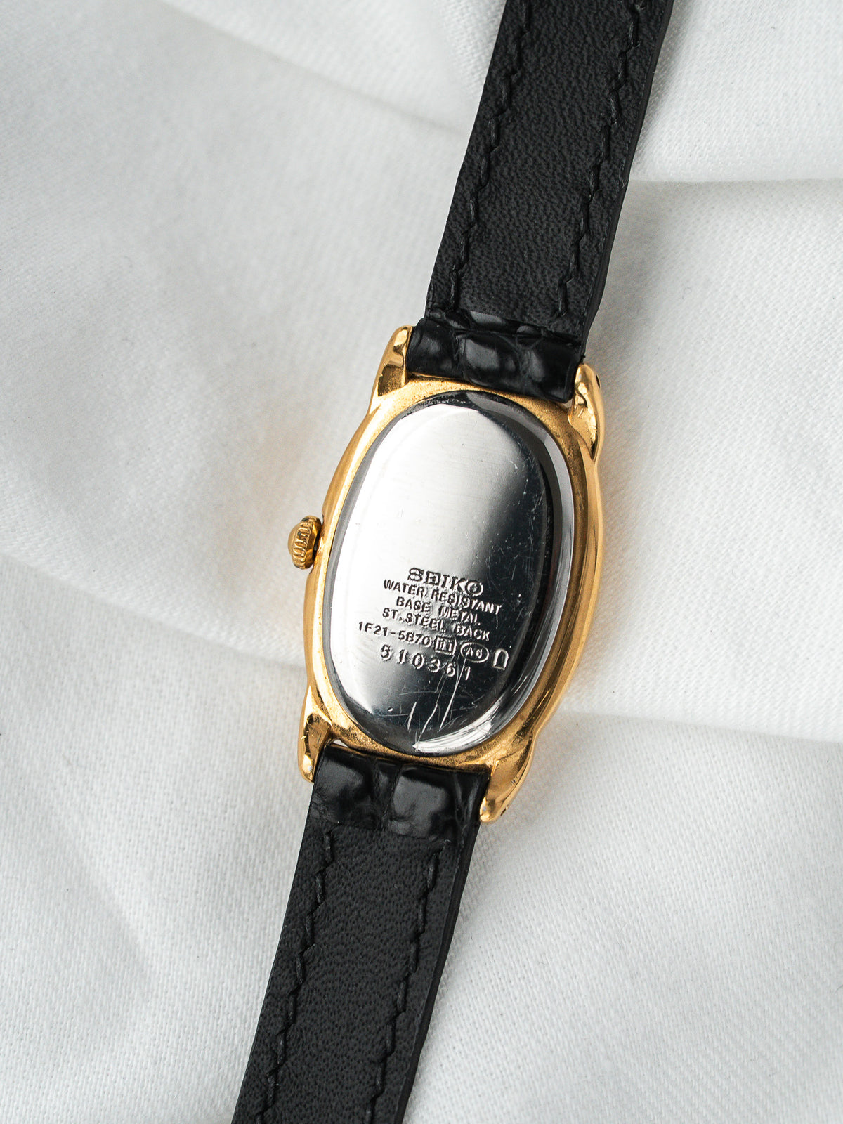 Dos de montre Seiko vintage en acier plaqué or avec bracelet cuir noir
