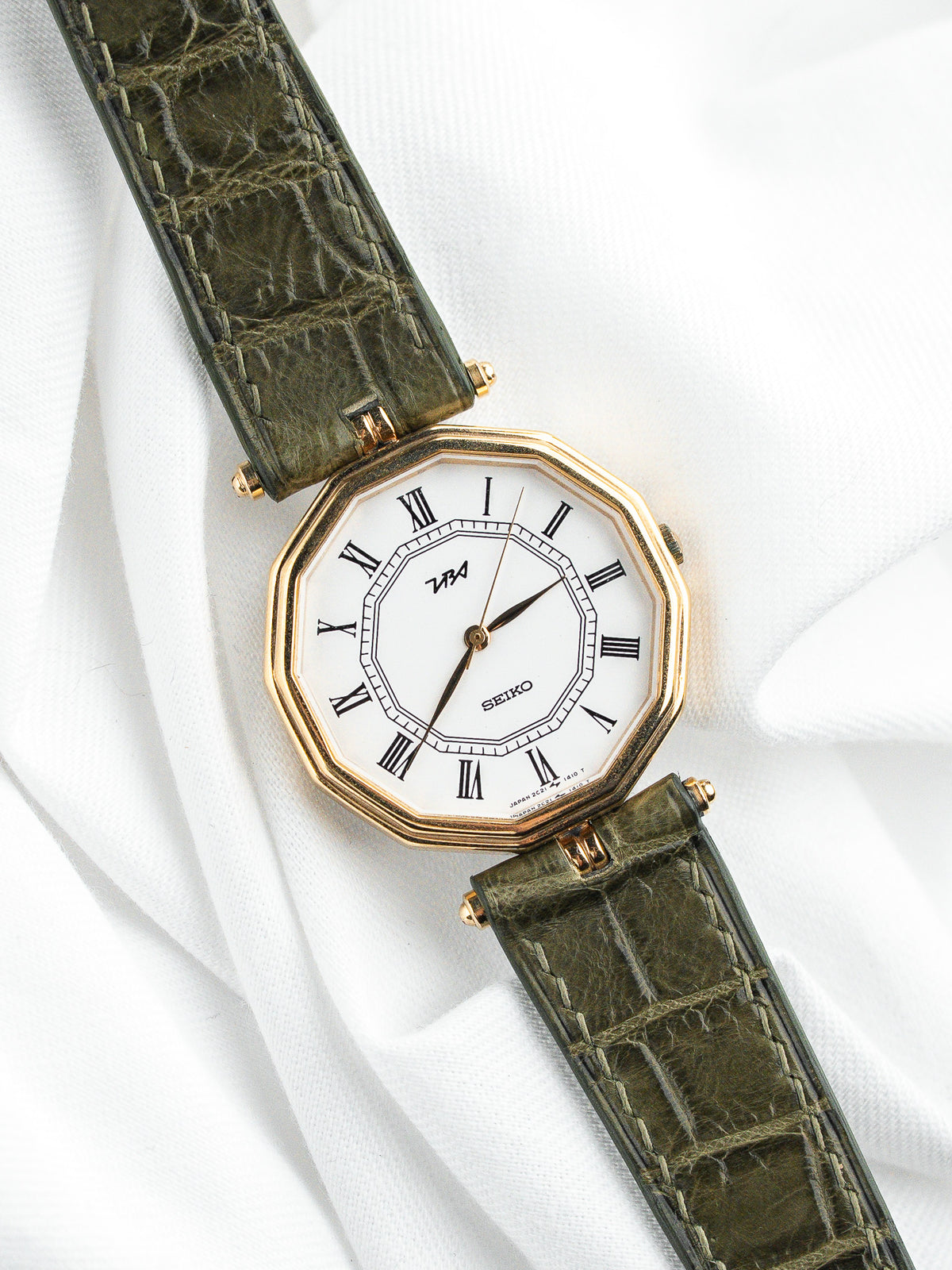 Montre Seiko vintage à boîtier octogonal doré et bracelet en cuir vert olive.