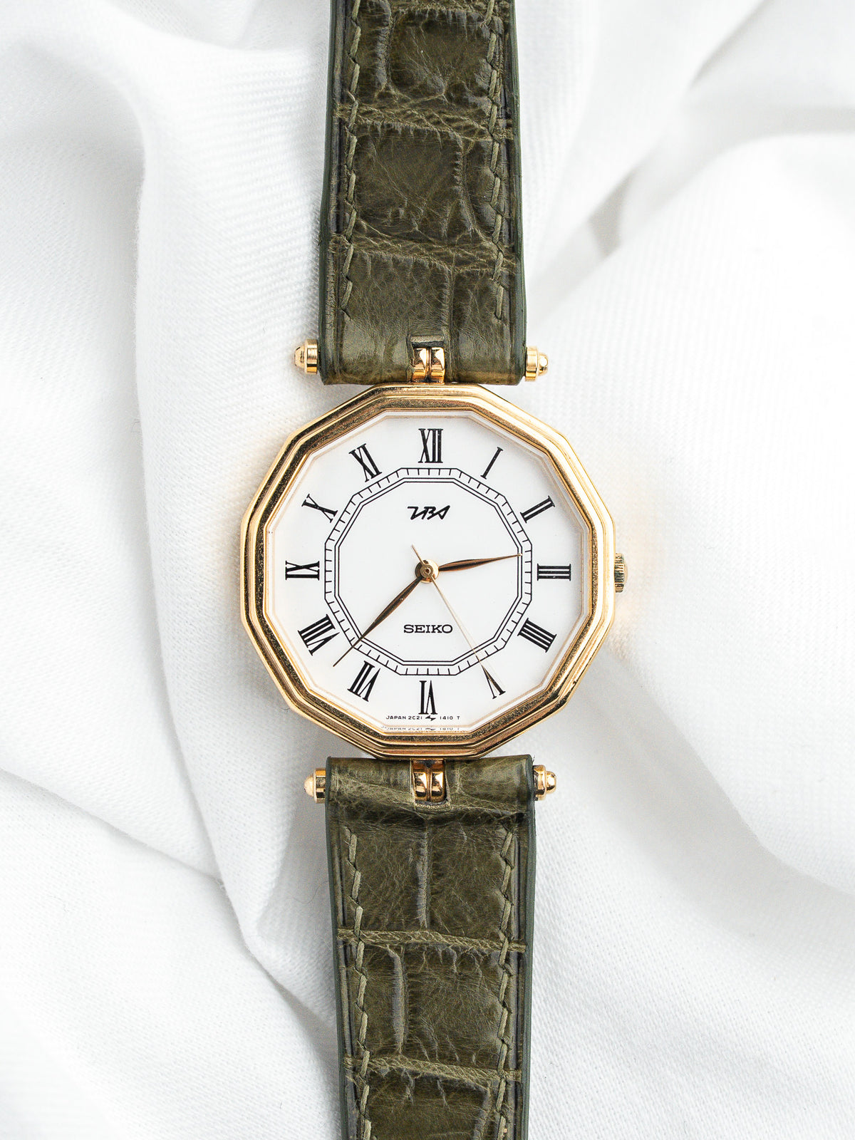 Montre Seiko vintage avec boîtier octogonal doré et bracelet en cuir vert olive.