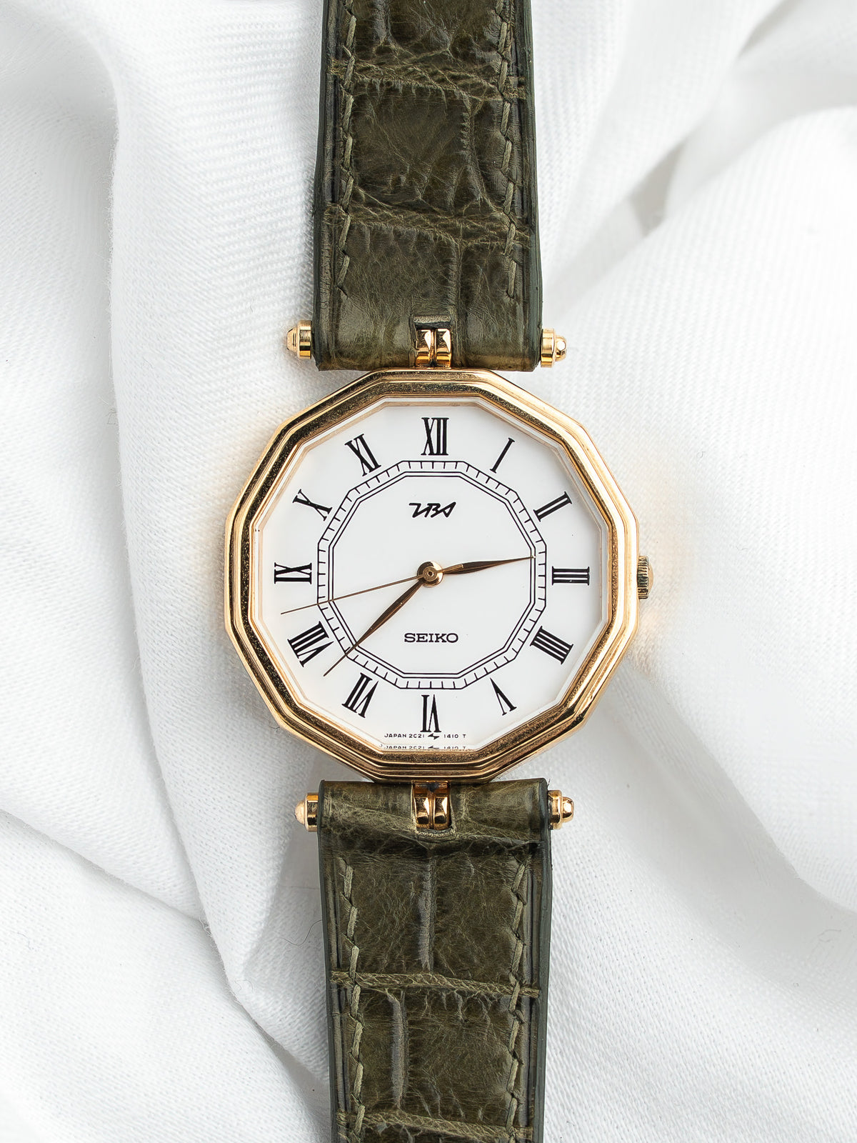 Montre Seiko vintage avec cadran blanc octogonal et bracelet en cuir vert olive.