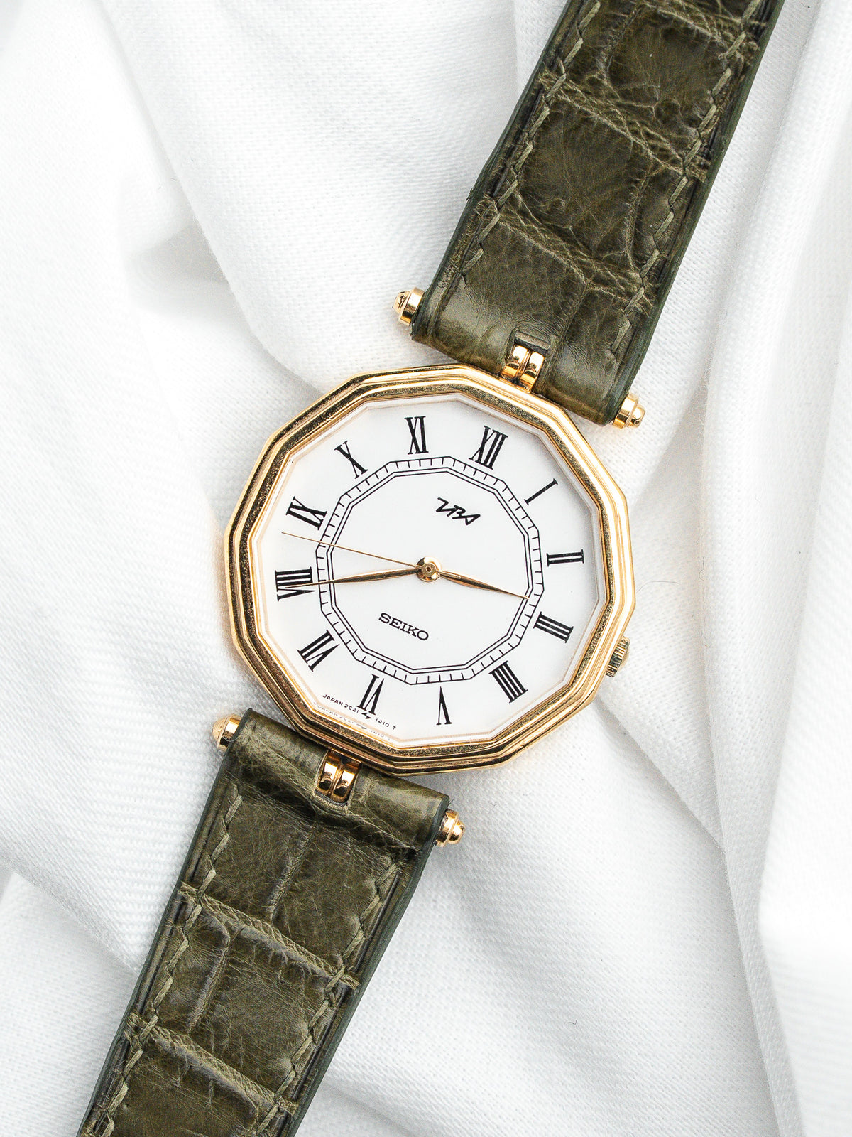 Montre Seiko vintage avec cadran blanc octogonal et bracelet en cuir vert olive.