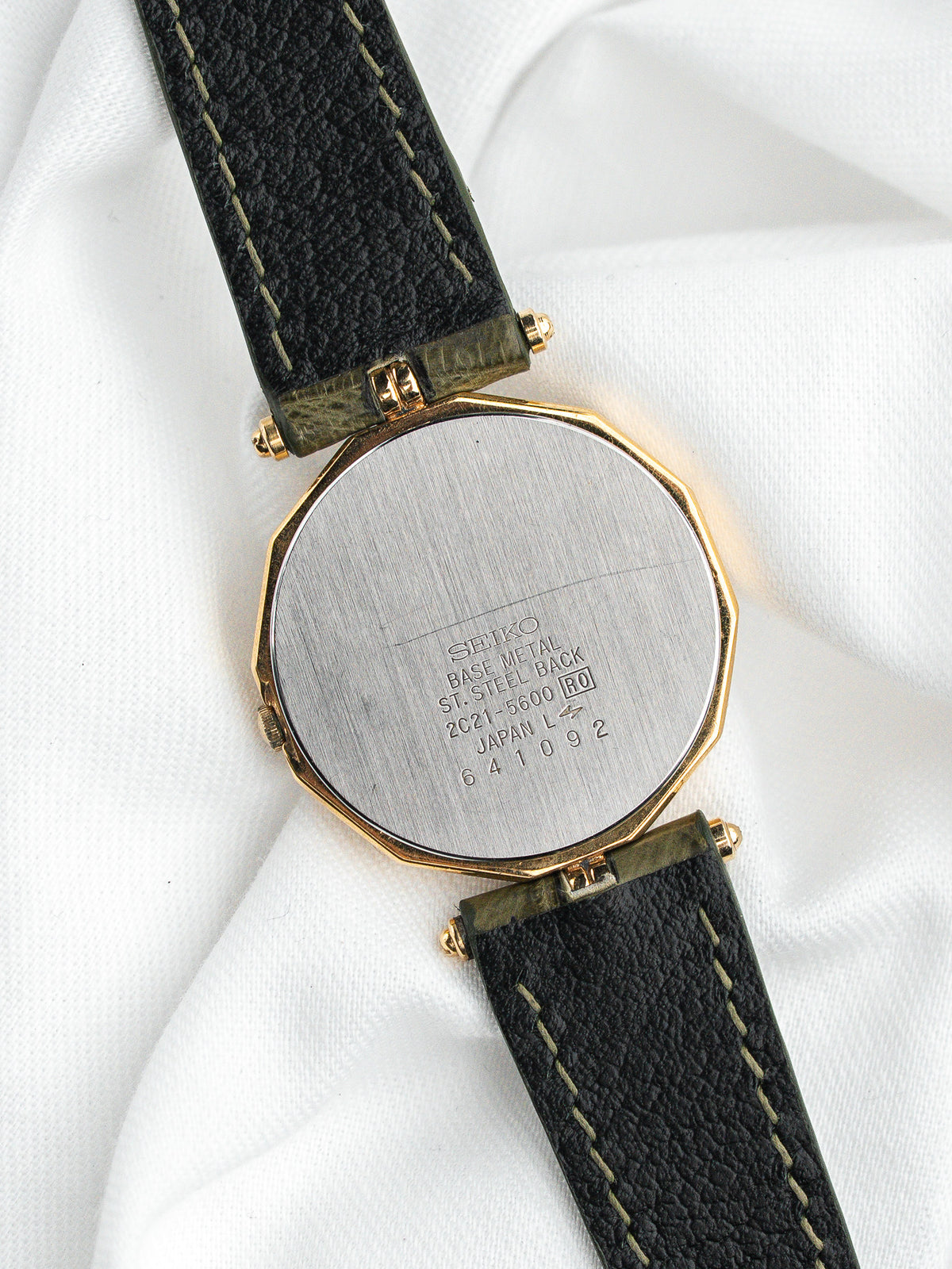 Dos d'une montre Seiko vintage avec boîtier octogonal doré et bracelet en cuir noir.