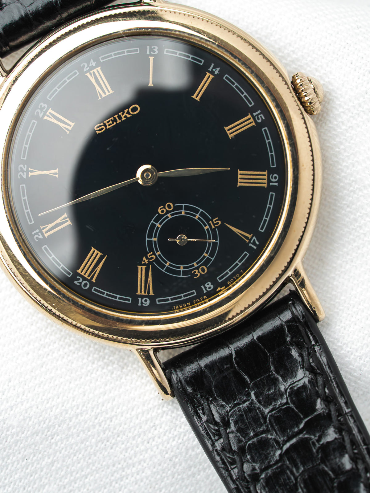 Seiko vintage watch with black dial, gold Roman numerals, and black leather strap