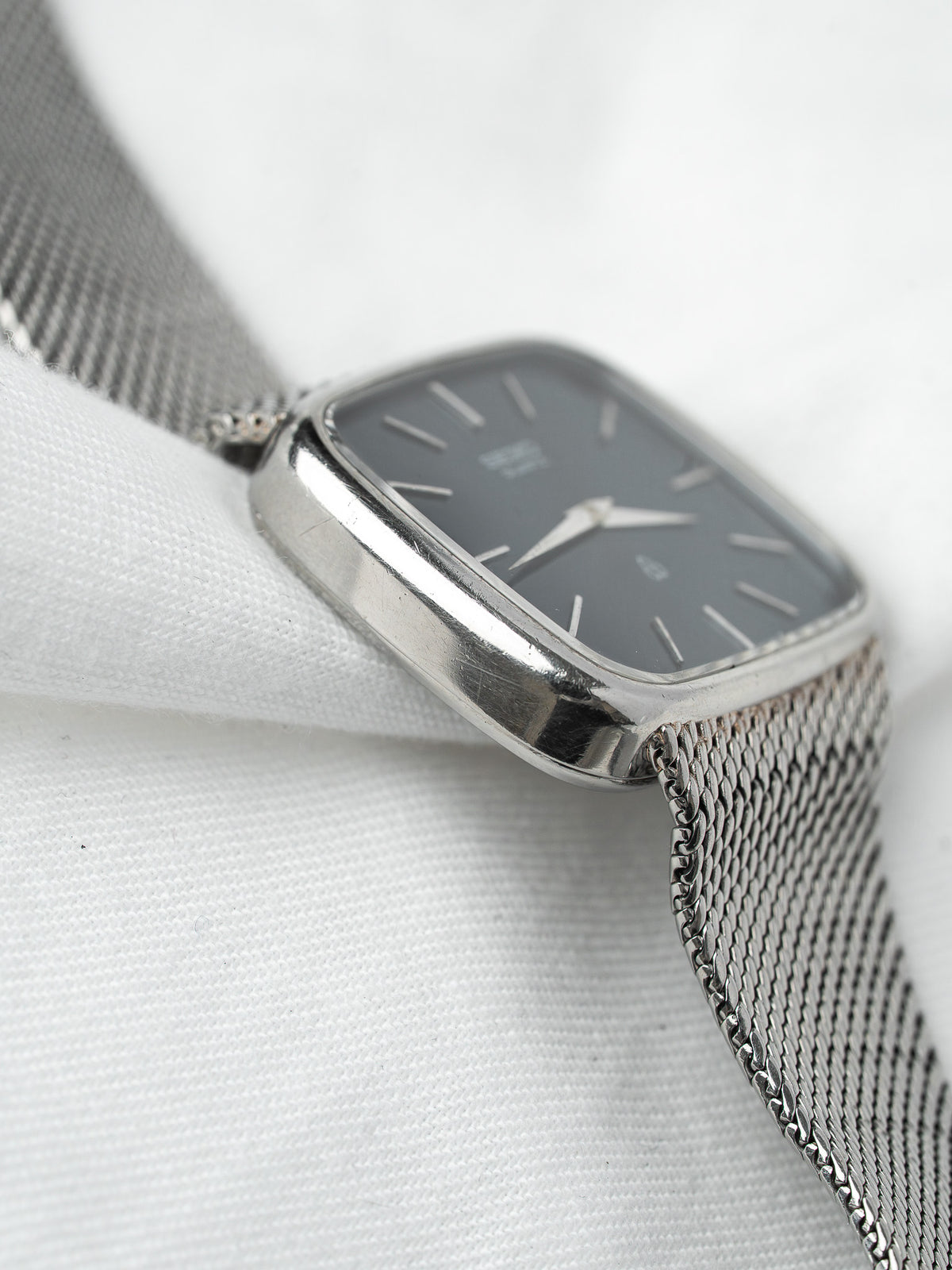 Vintage Omega watch with gray dial, silver mesh bracelet, and rectangular case
